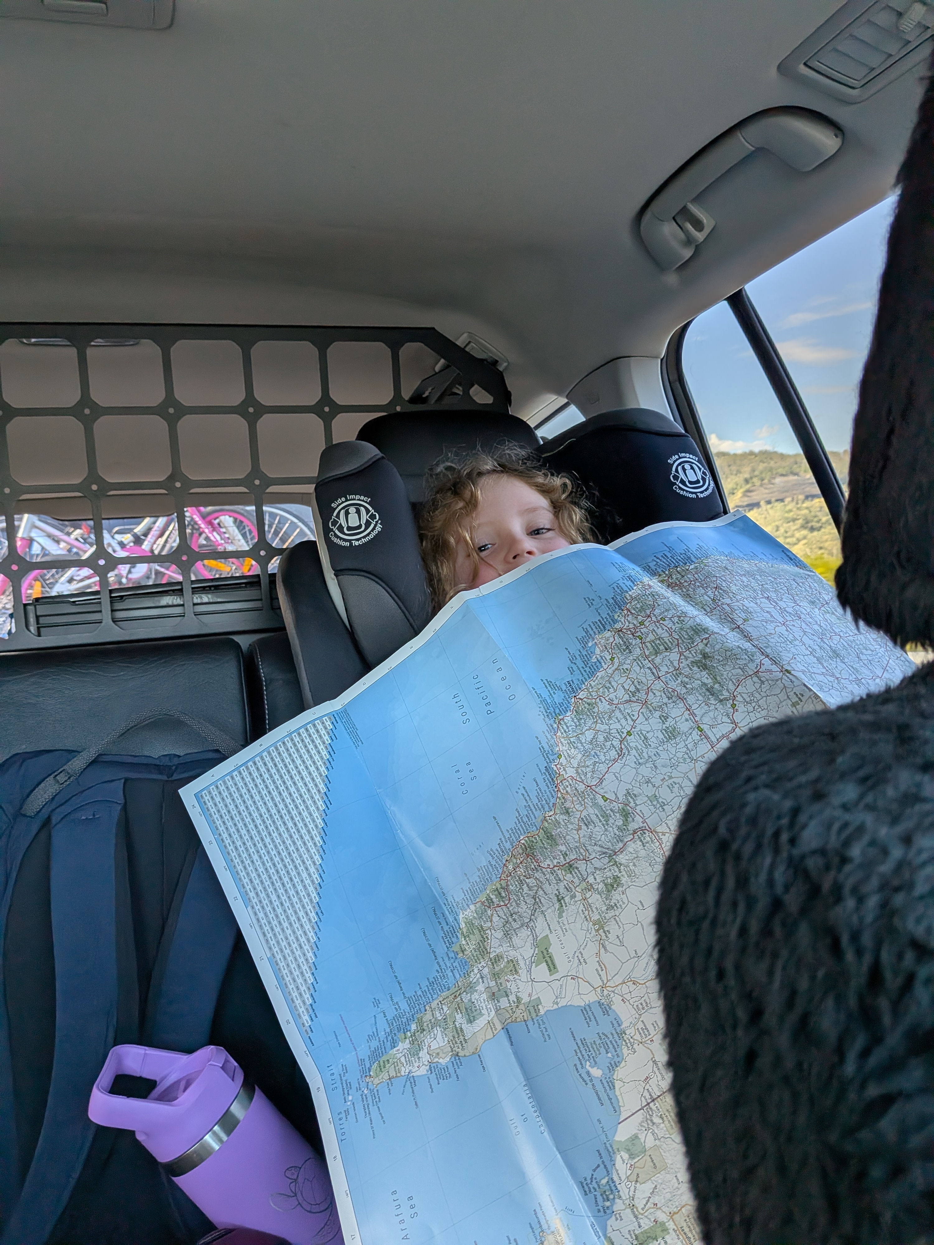 Peeking over the map of Australia in the back seat of Reg