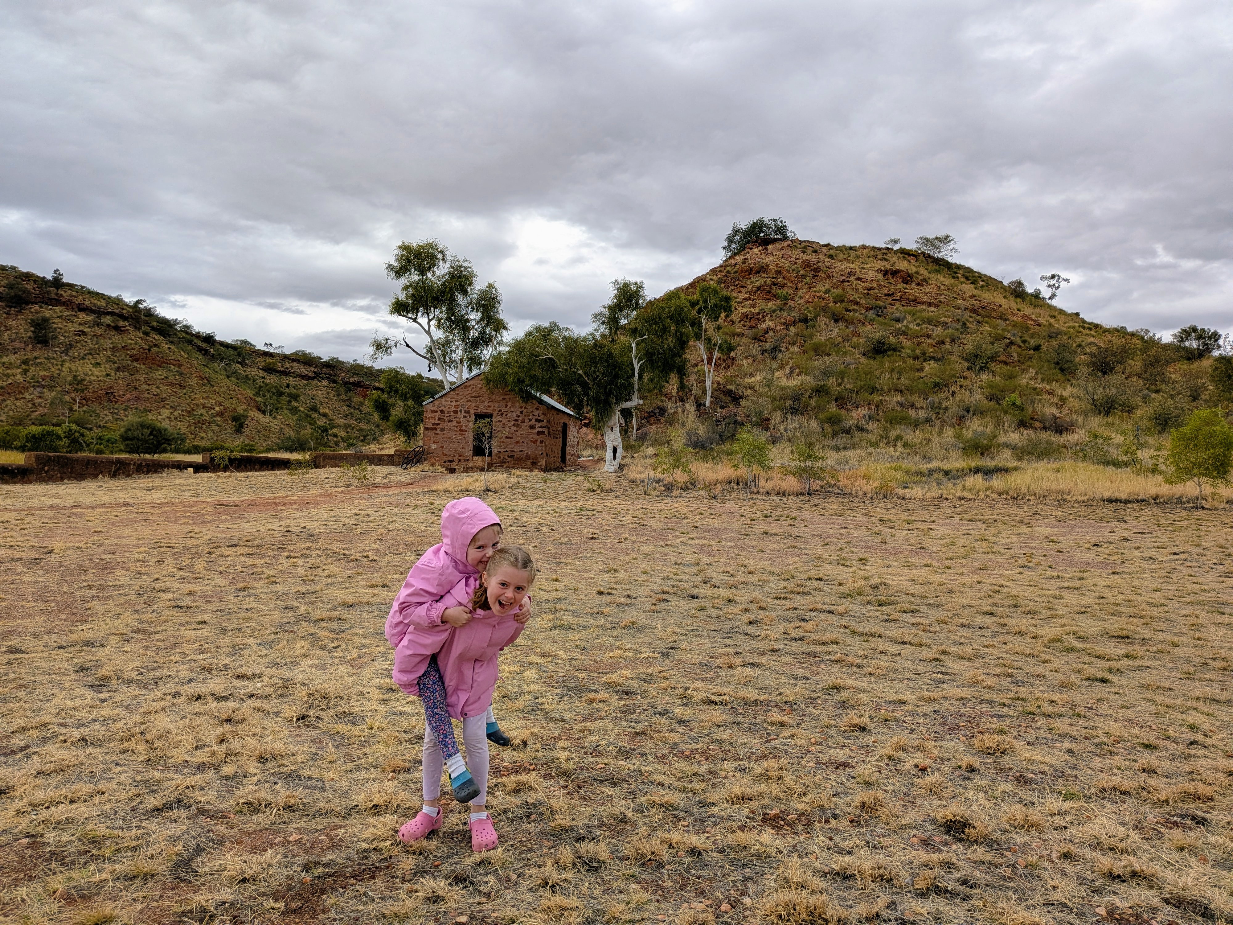 The girls piggyback in front of the old Barrow Creek Telegraph Station