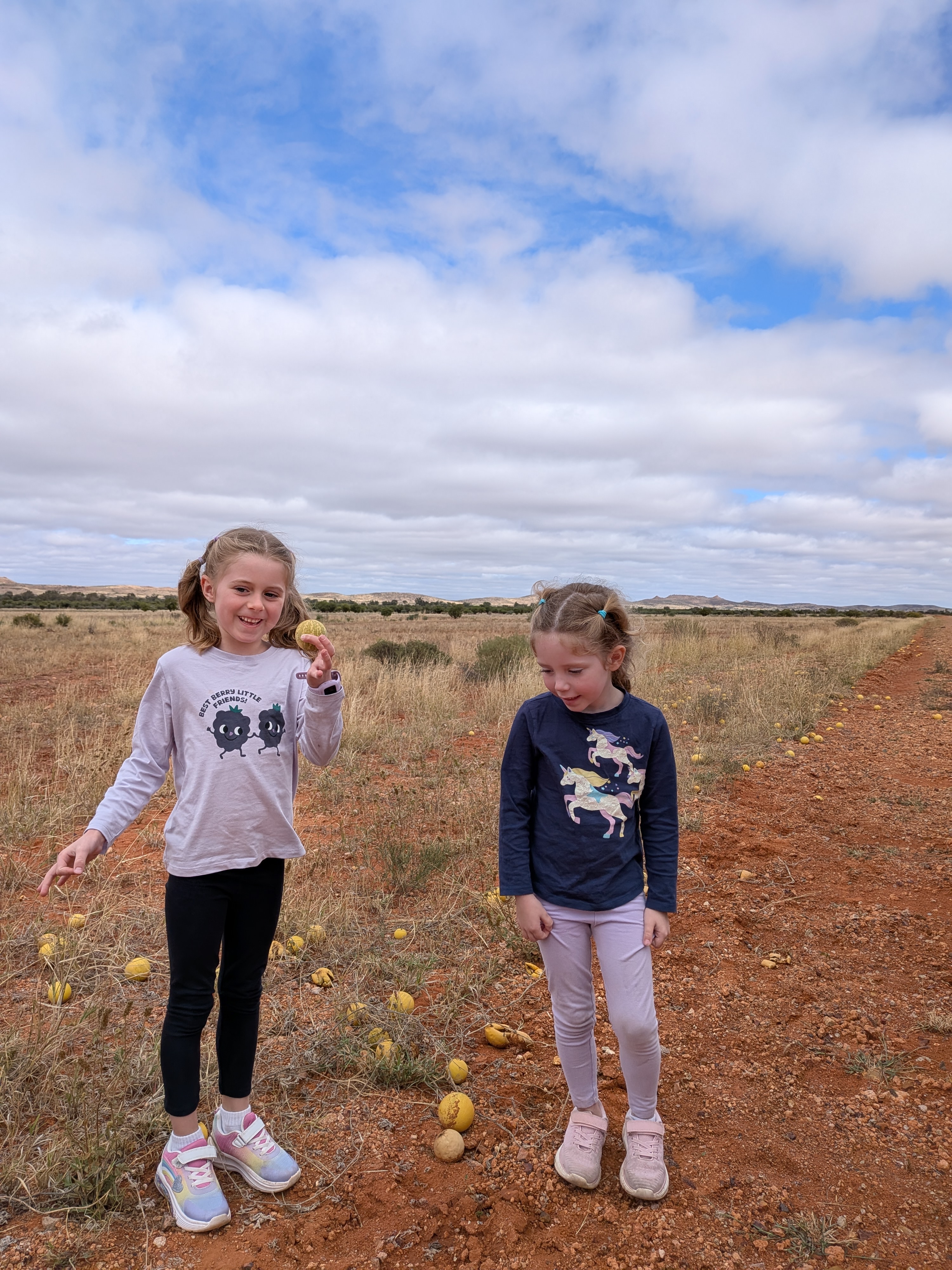 The girls with the camel melons on the red dirt