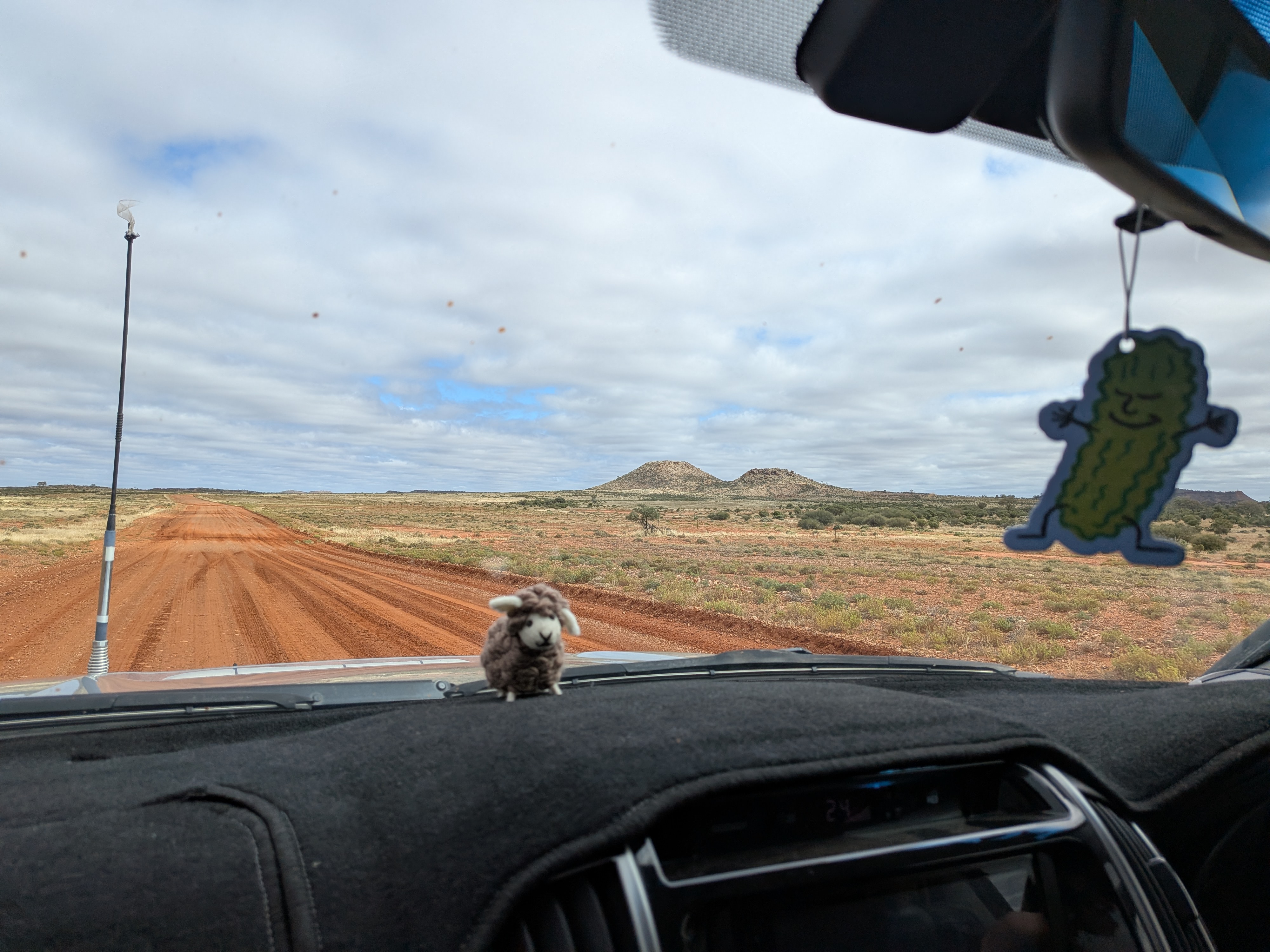 Dashboard sheep and pickle air freshener on the red dirt road