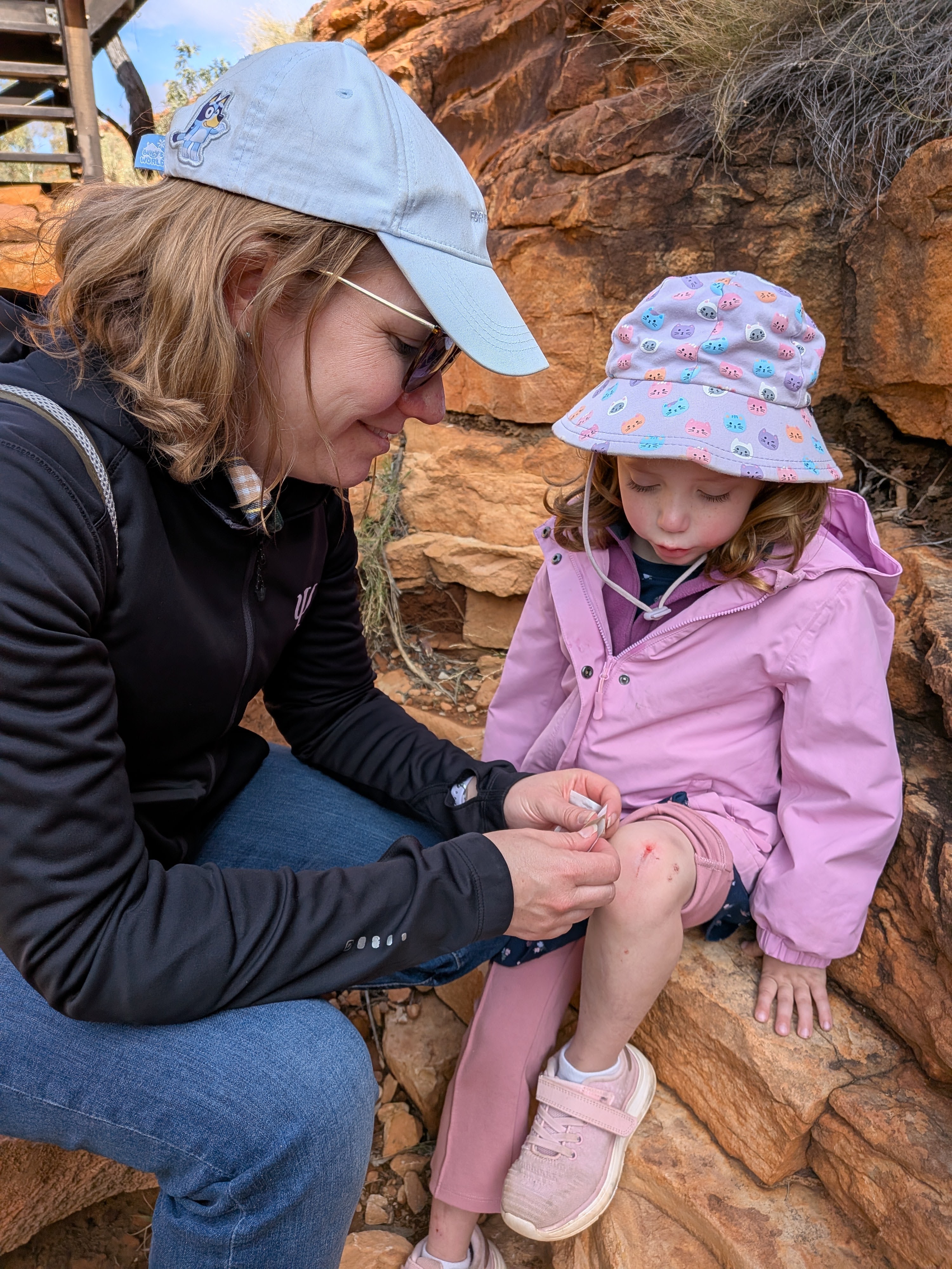 Erin patching up Leah's scraped knee on the rocks