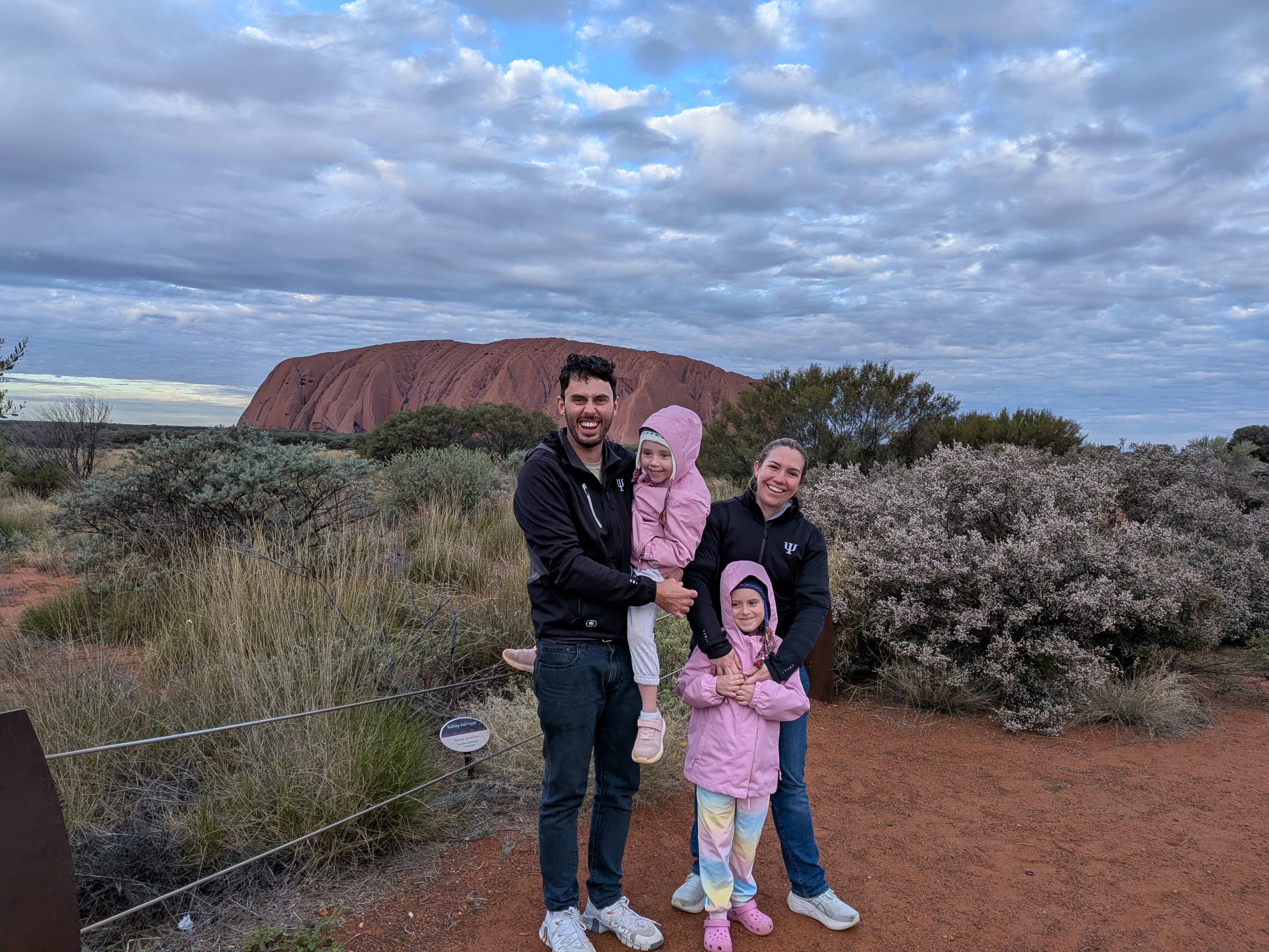 Family photo with Uluru behind on a cloudy evening