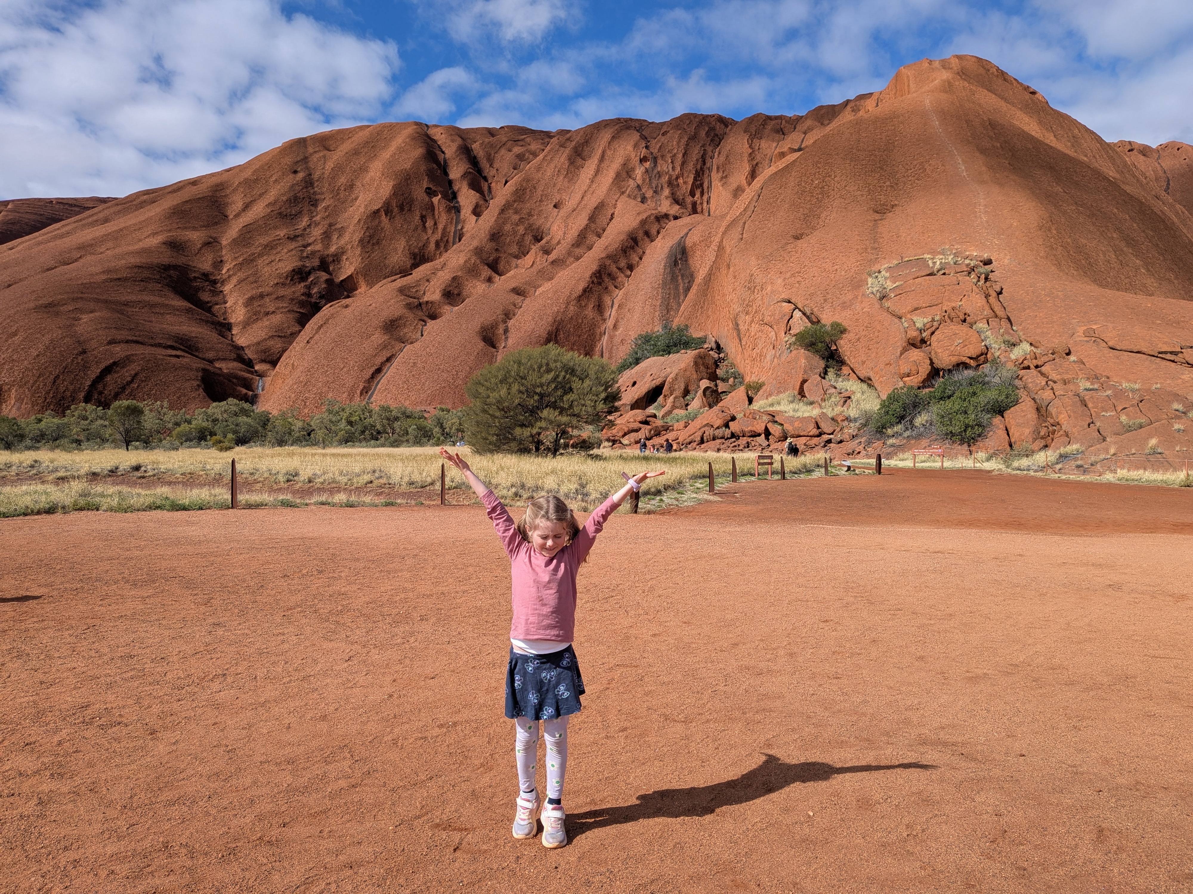 Leah with her arms up in front of Uluru