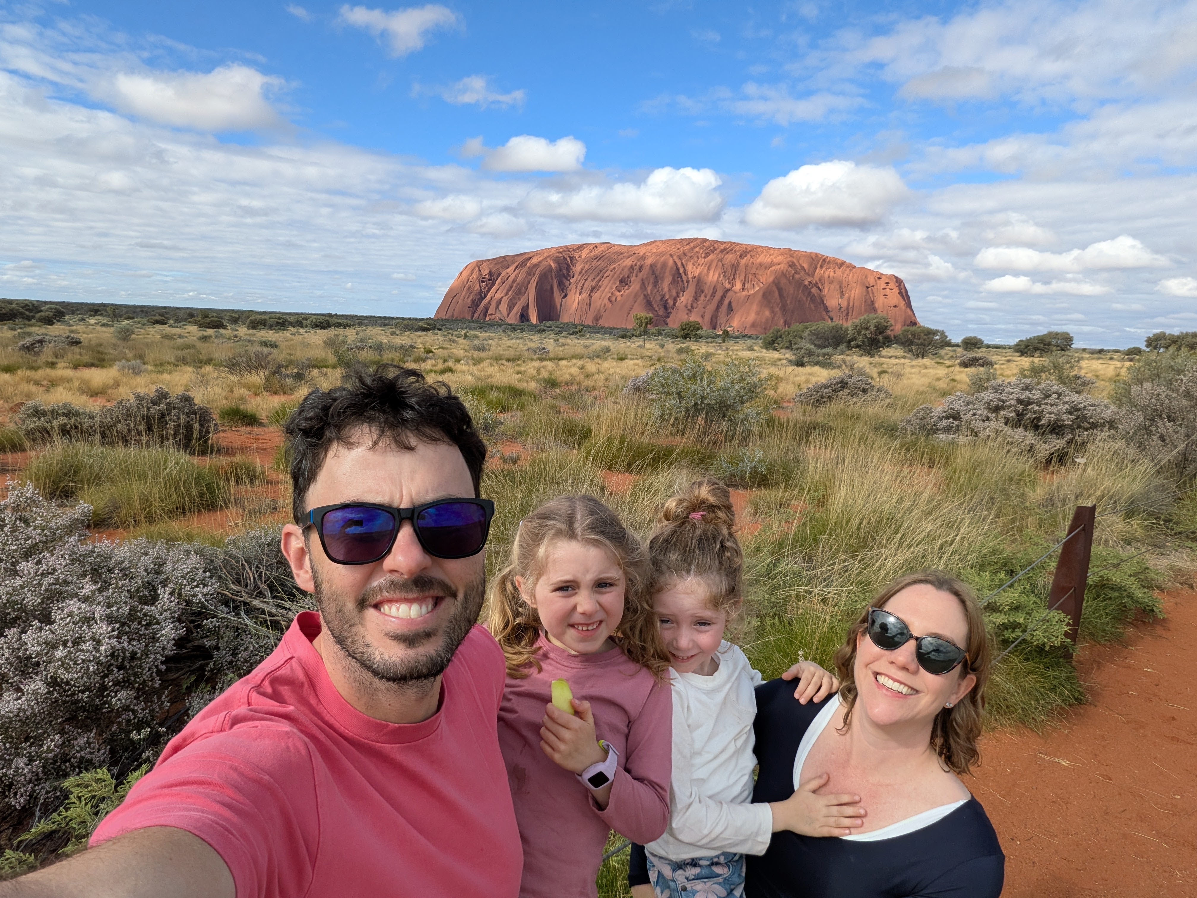 Family selfie with Uluru from a distance in the sunshine