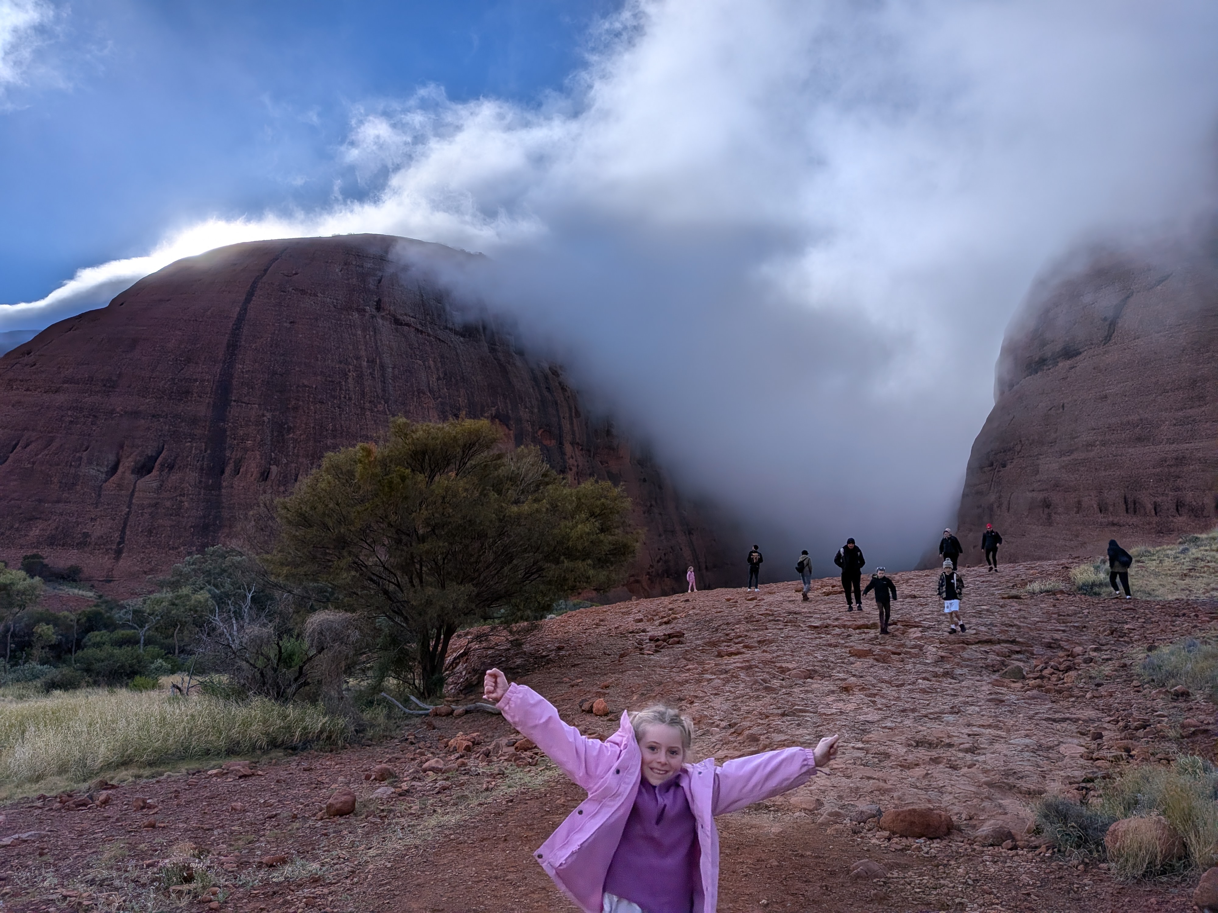 Hazel arms up with fog pouring through the domes at Kata Tjuta