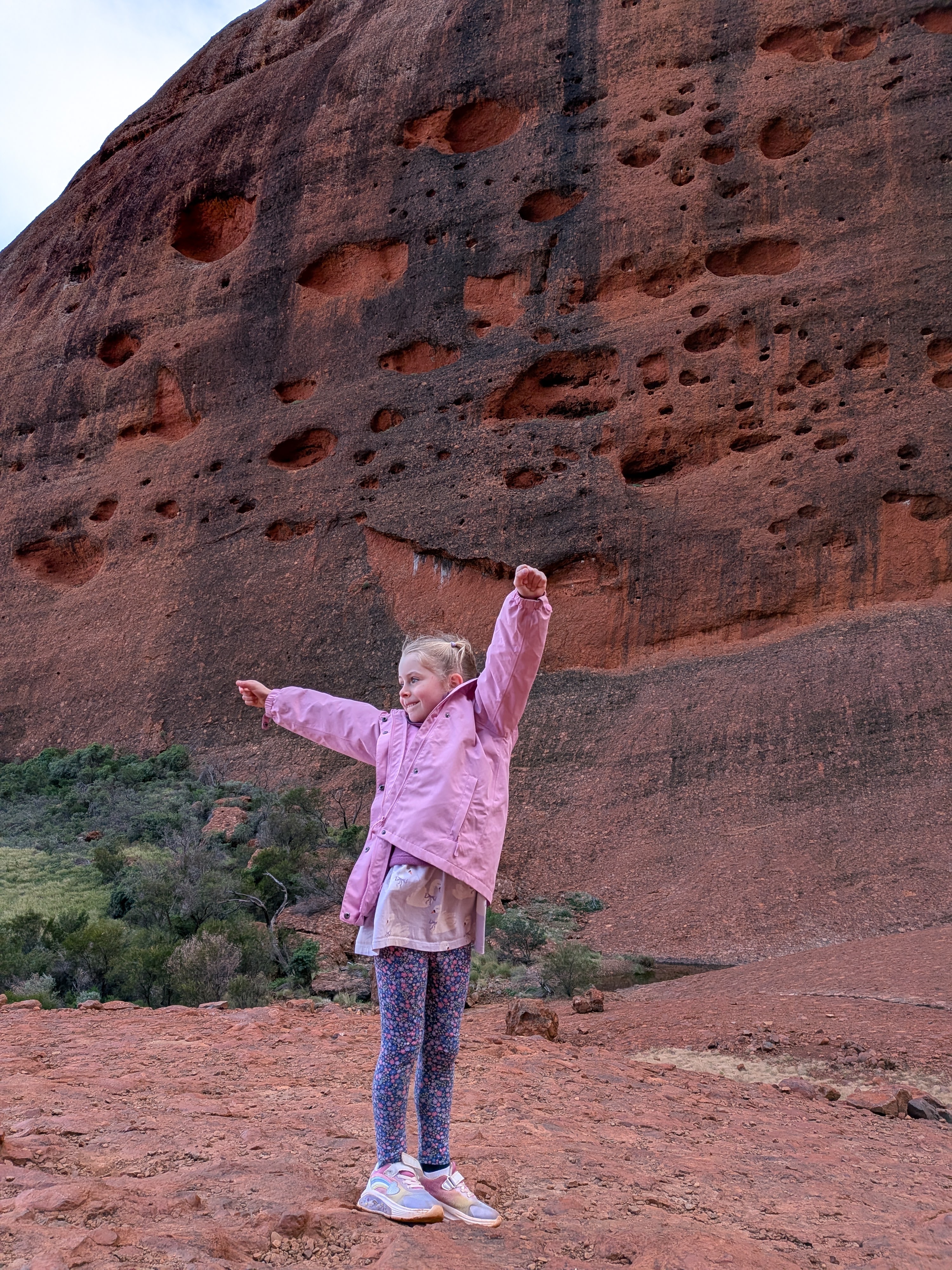 Hazel arms up in front of the honeycomb rock face at Kata Tjuta
