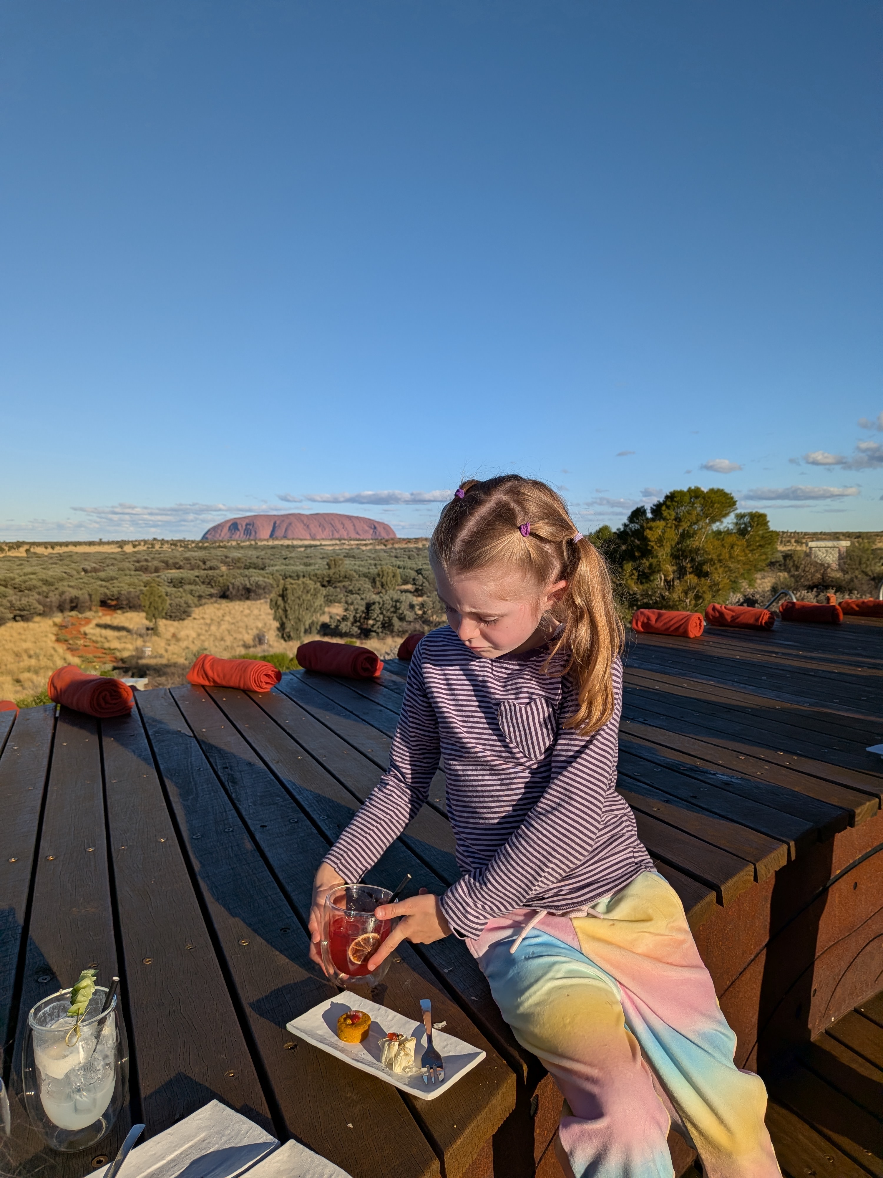 Hazel with cocktail and canapes at the Wintjiri Wiru deck with Uluru behind