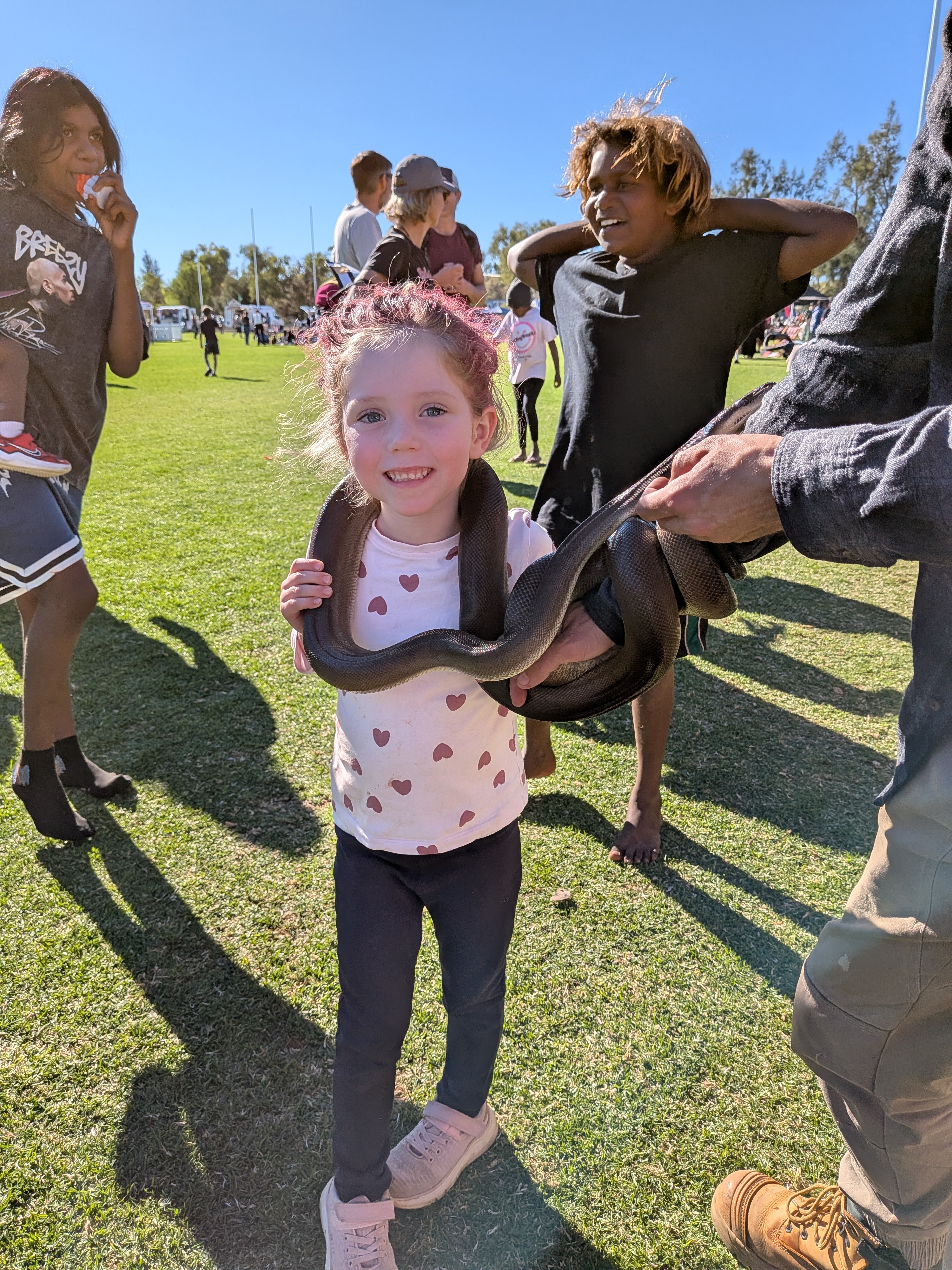 Leah grinning with pink hair holding a snake at the Newlandia Festival