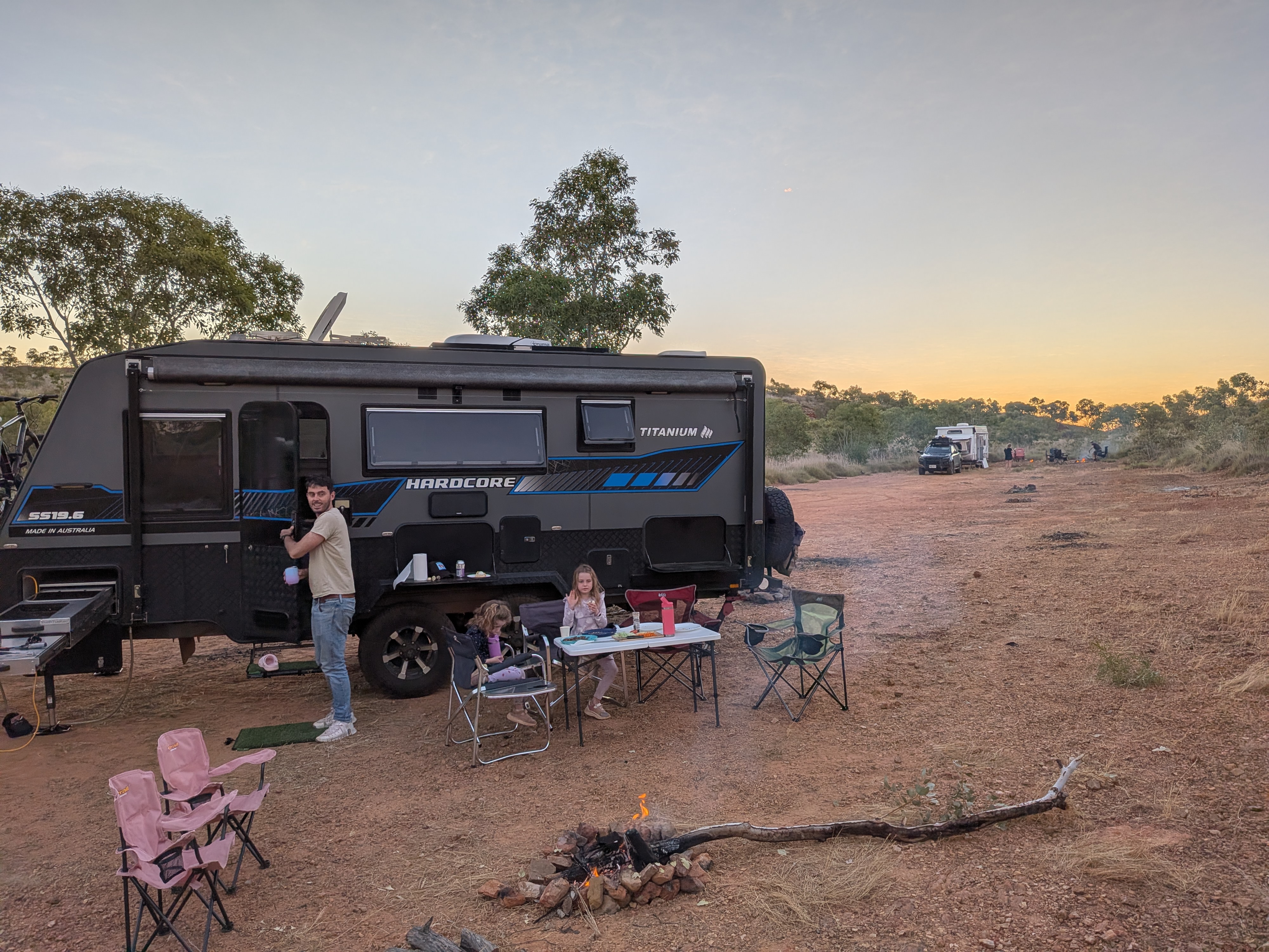 Camp set up at Churchill's Head free camp with the caravan, camp table and fire going as the sun sets