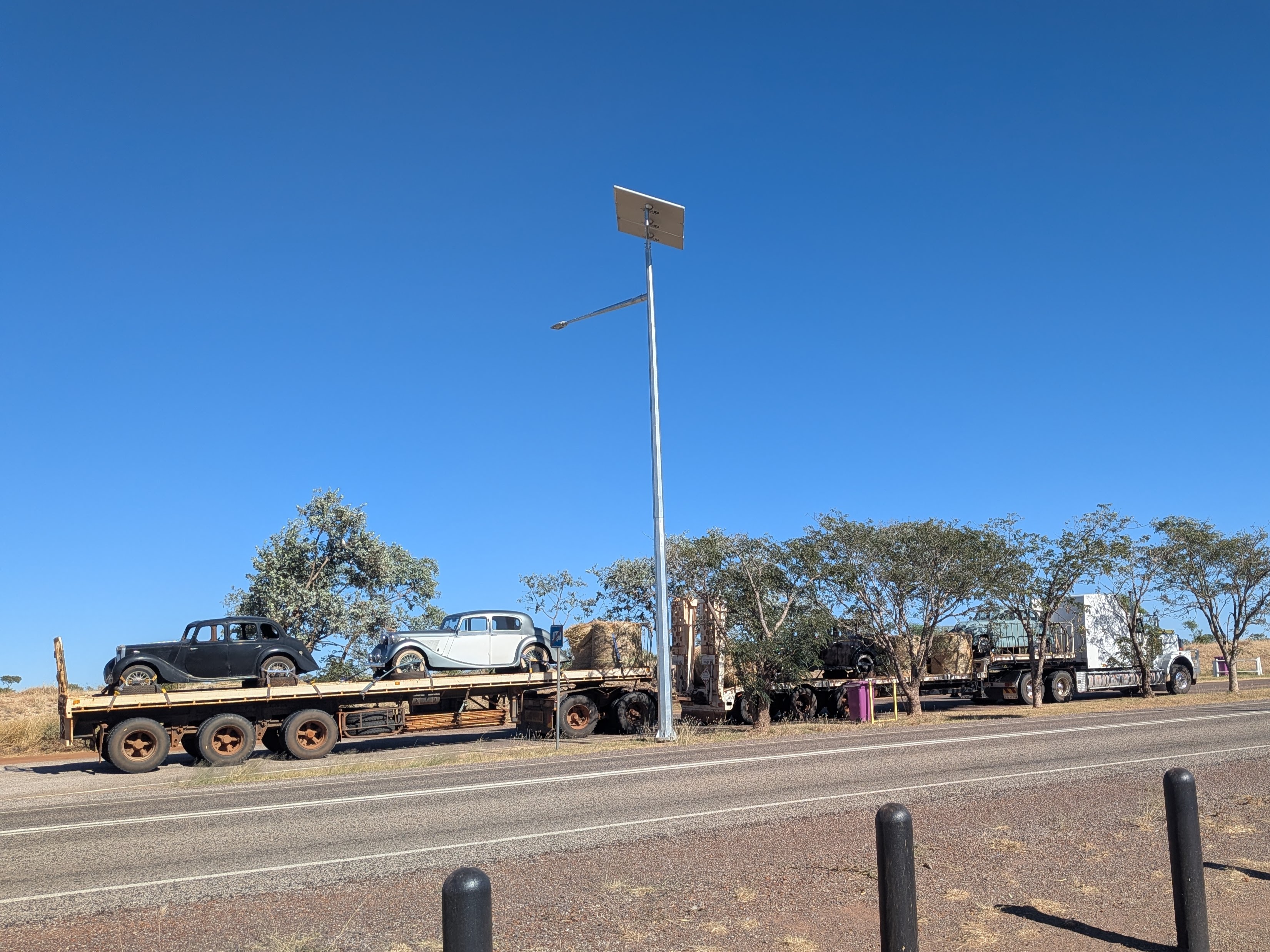 A road train loaded with classic cars and hay bales parked at Renner Springs