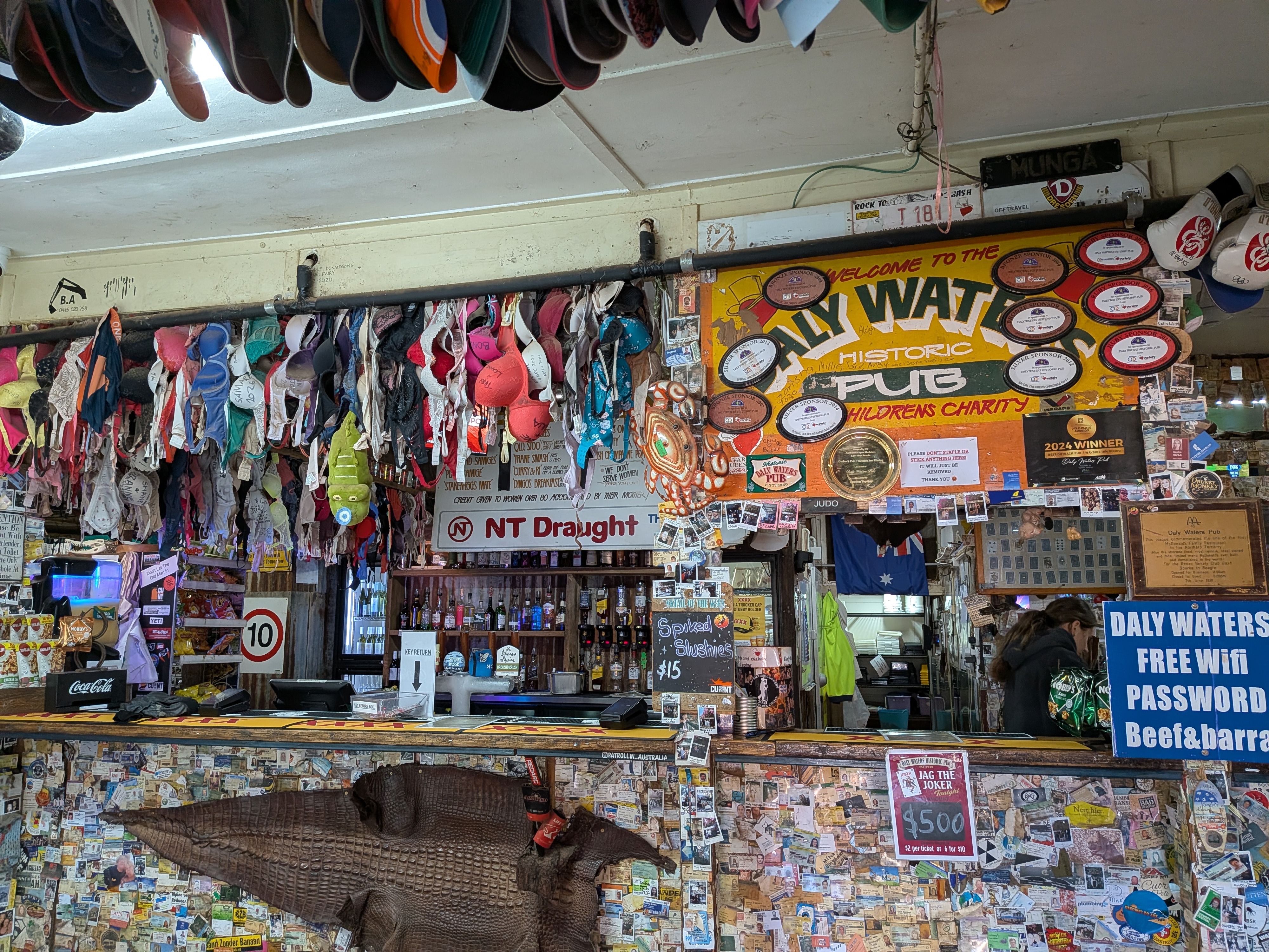 The wall of bras above the bar with the Welcome to the Daly Waters Historic Pub sign