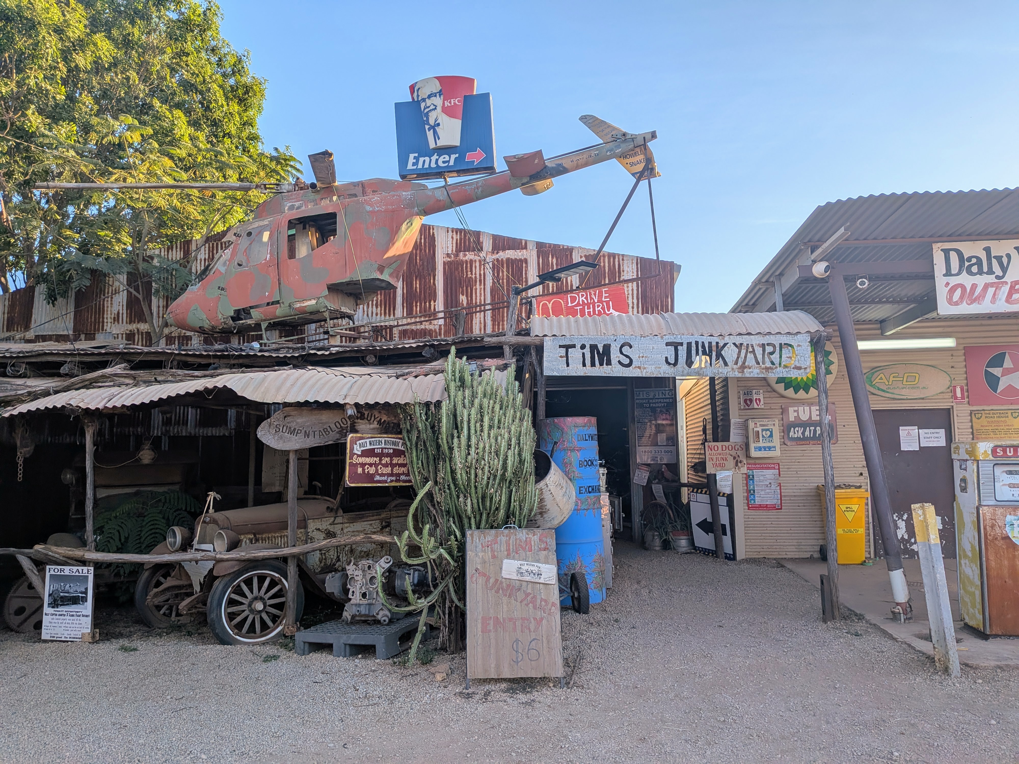 Tim's Junkyard entrance with a camouflage helicopter and KFC sign perched on the roof