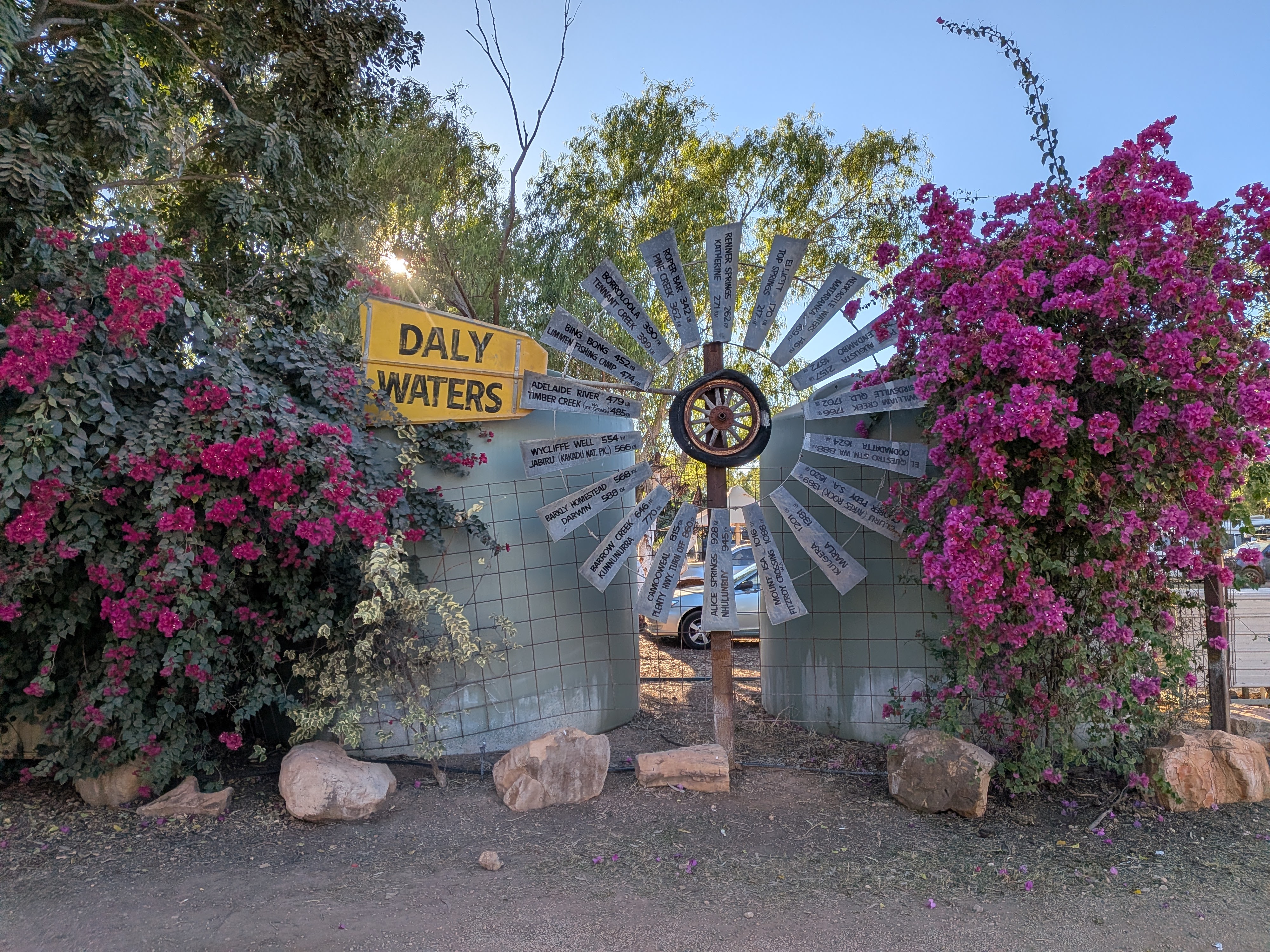 The Daly Waters windmill of hand-painted distance signs framed by pink bougainvillea