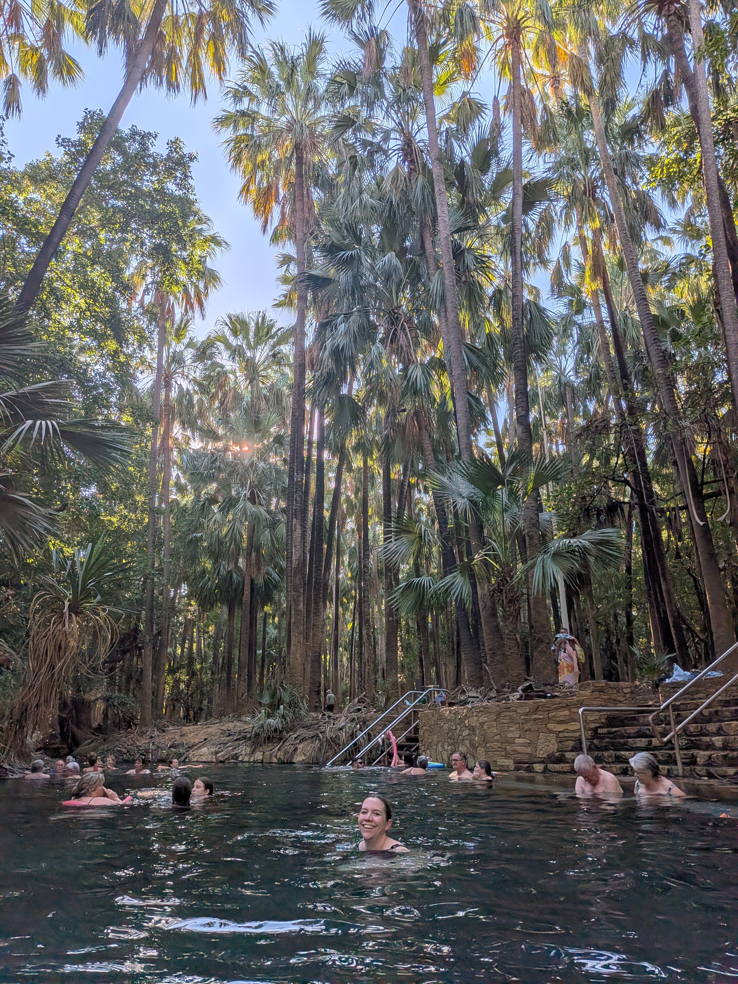 Erin mid-pool at the Mataranka Thermal Pool with towering palms all around