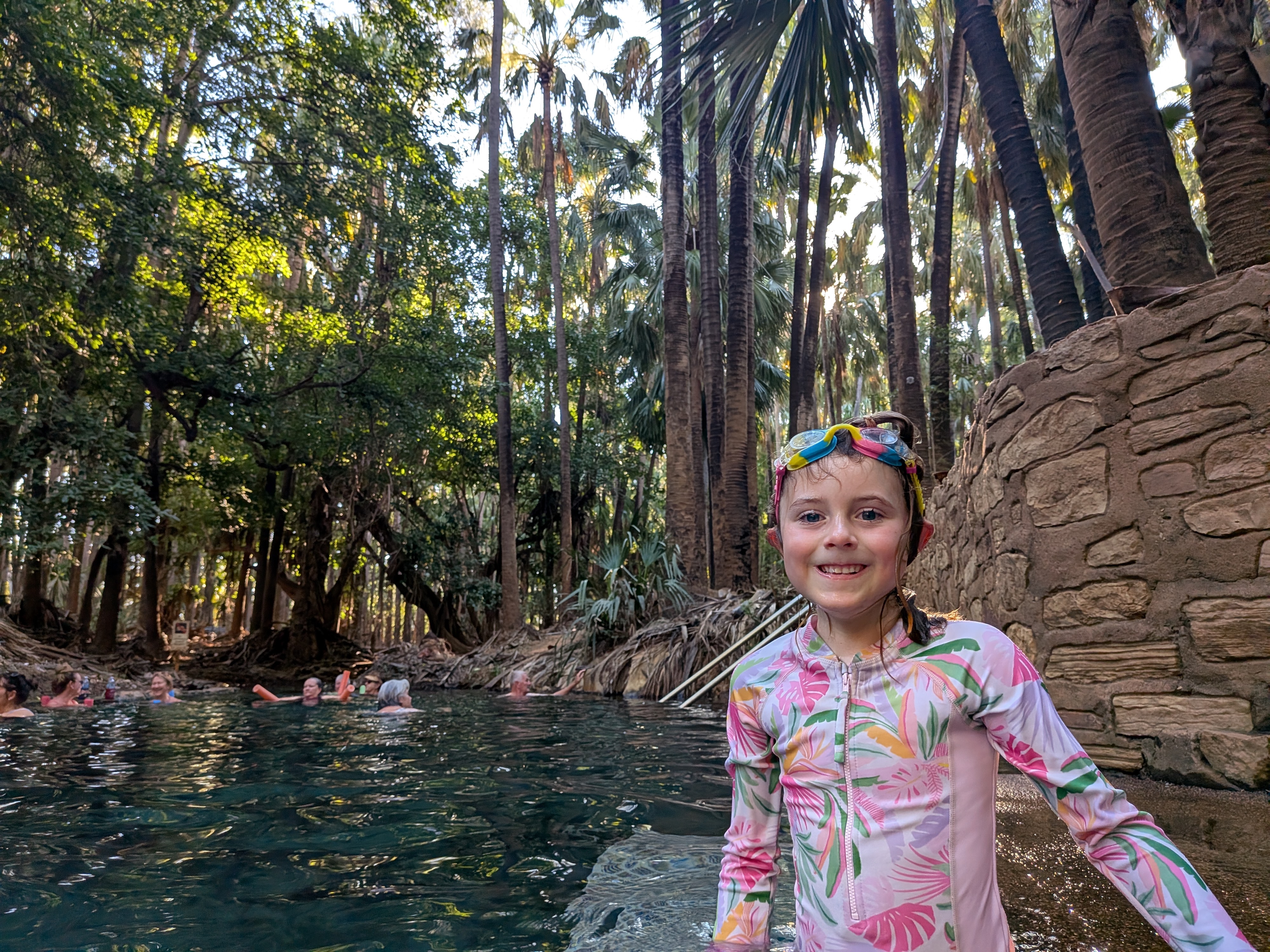 Hazel by the stone wall of the thermal pool with goggles at the ready
