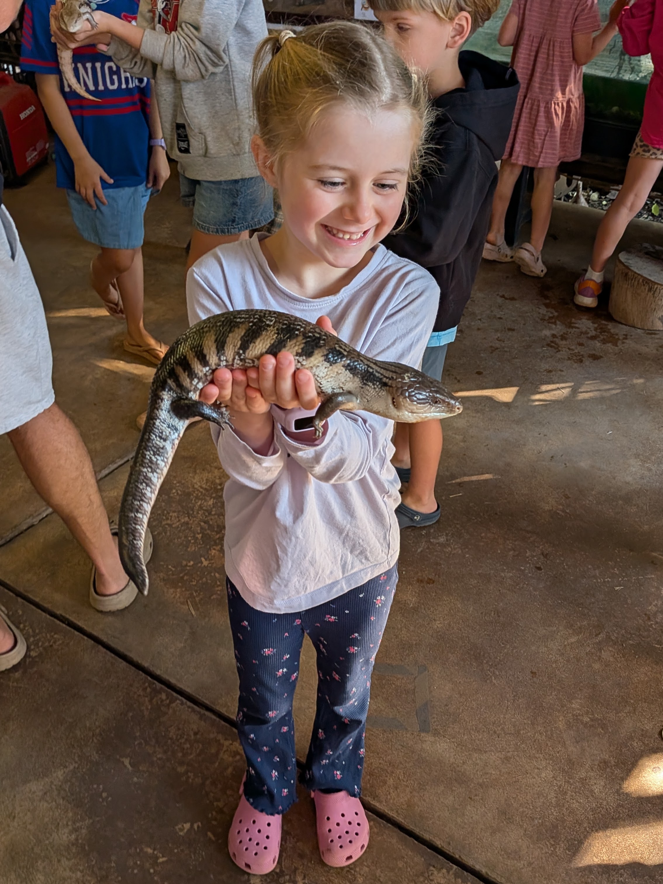 Hazel grinning as she holds a big blue-tongue lizard