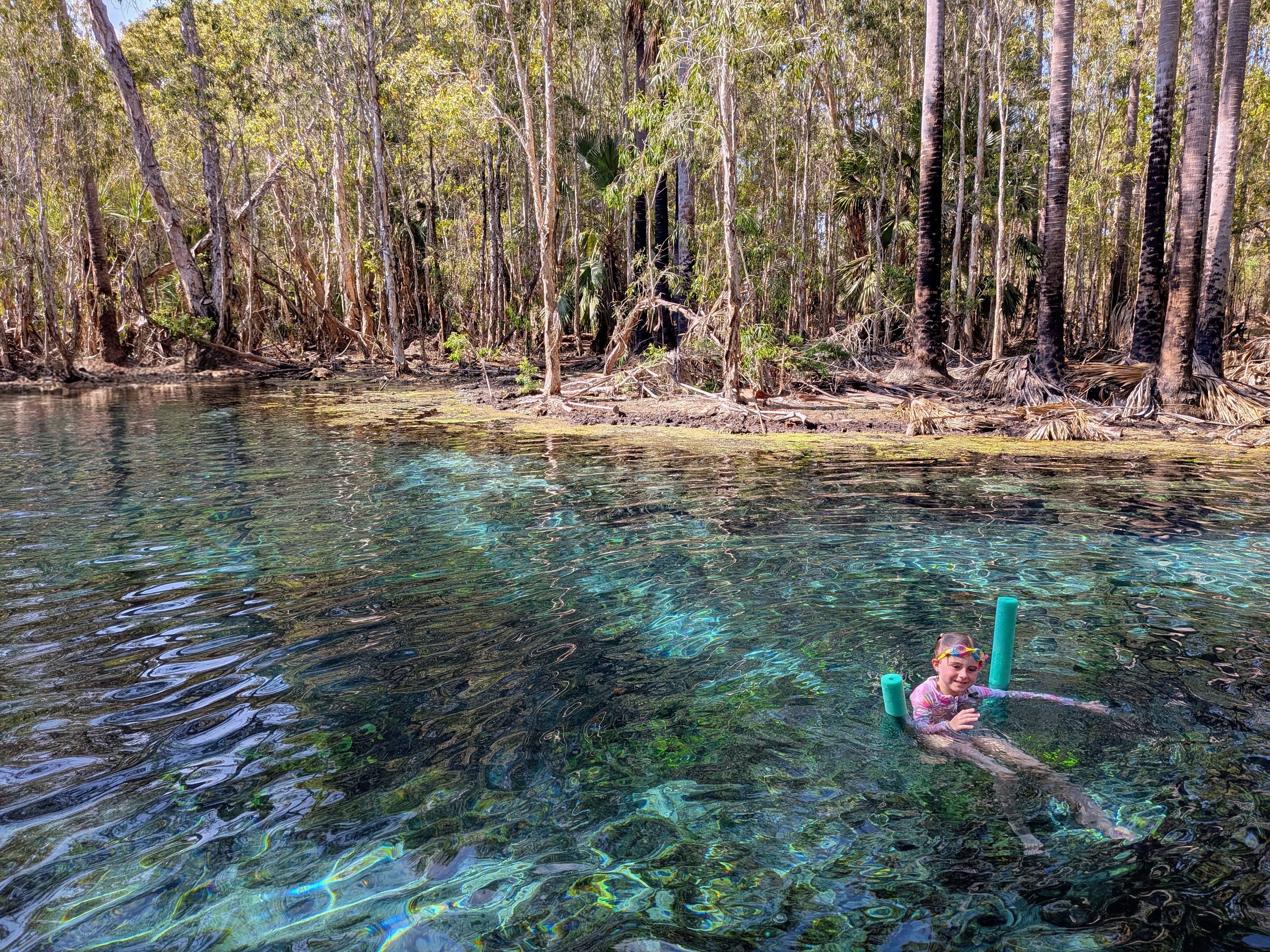 Hazel floating in the clear blue water with her noodle