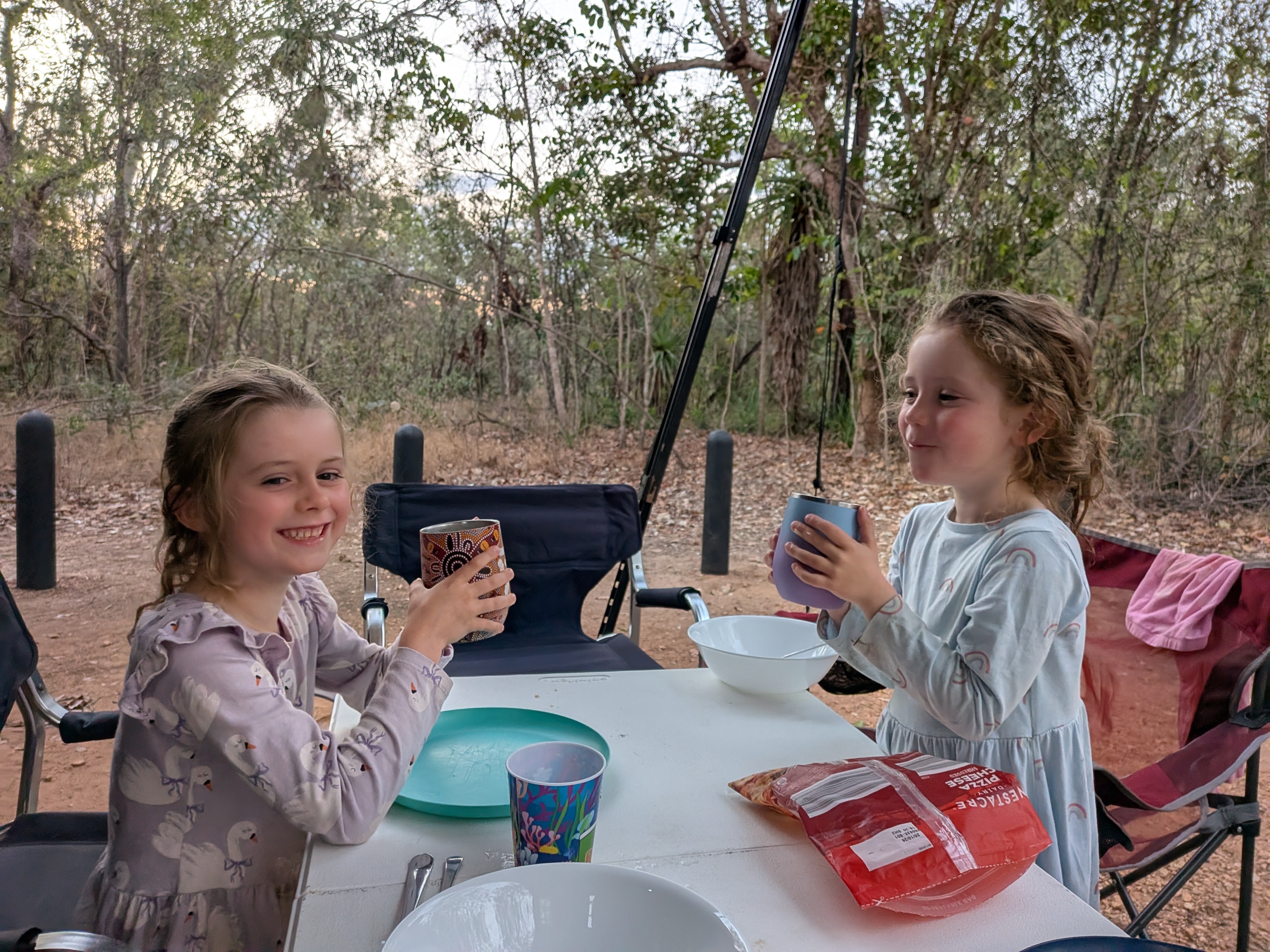 The girls in their pyjamas clinking cups at camp dinner after the swim