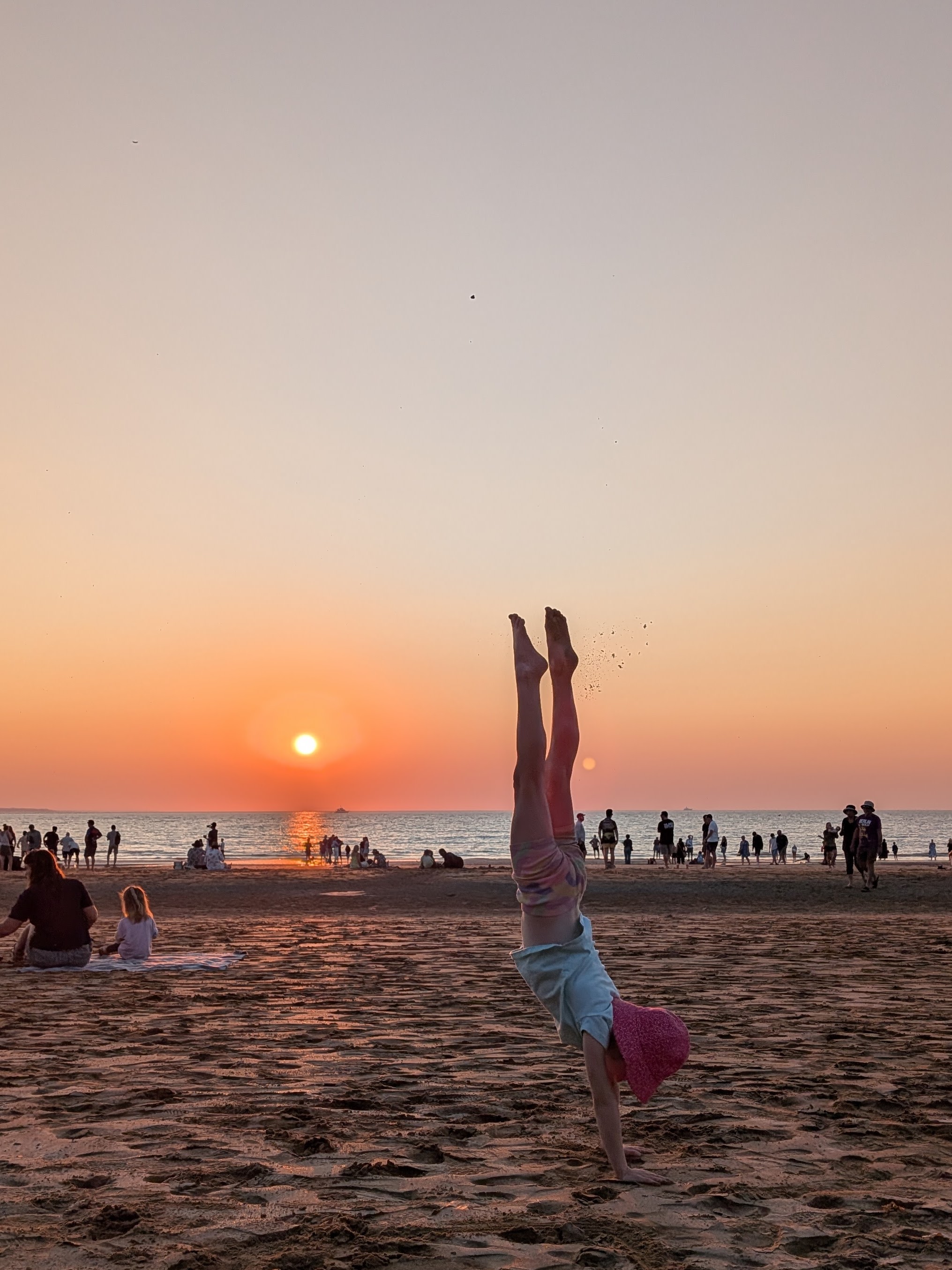 Hazel holding a handstand on the sand in front of the Mindil Beach sunset