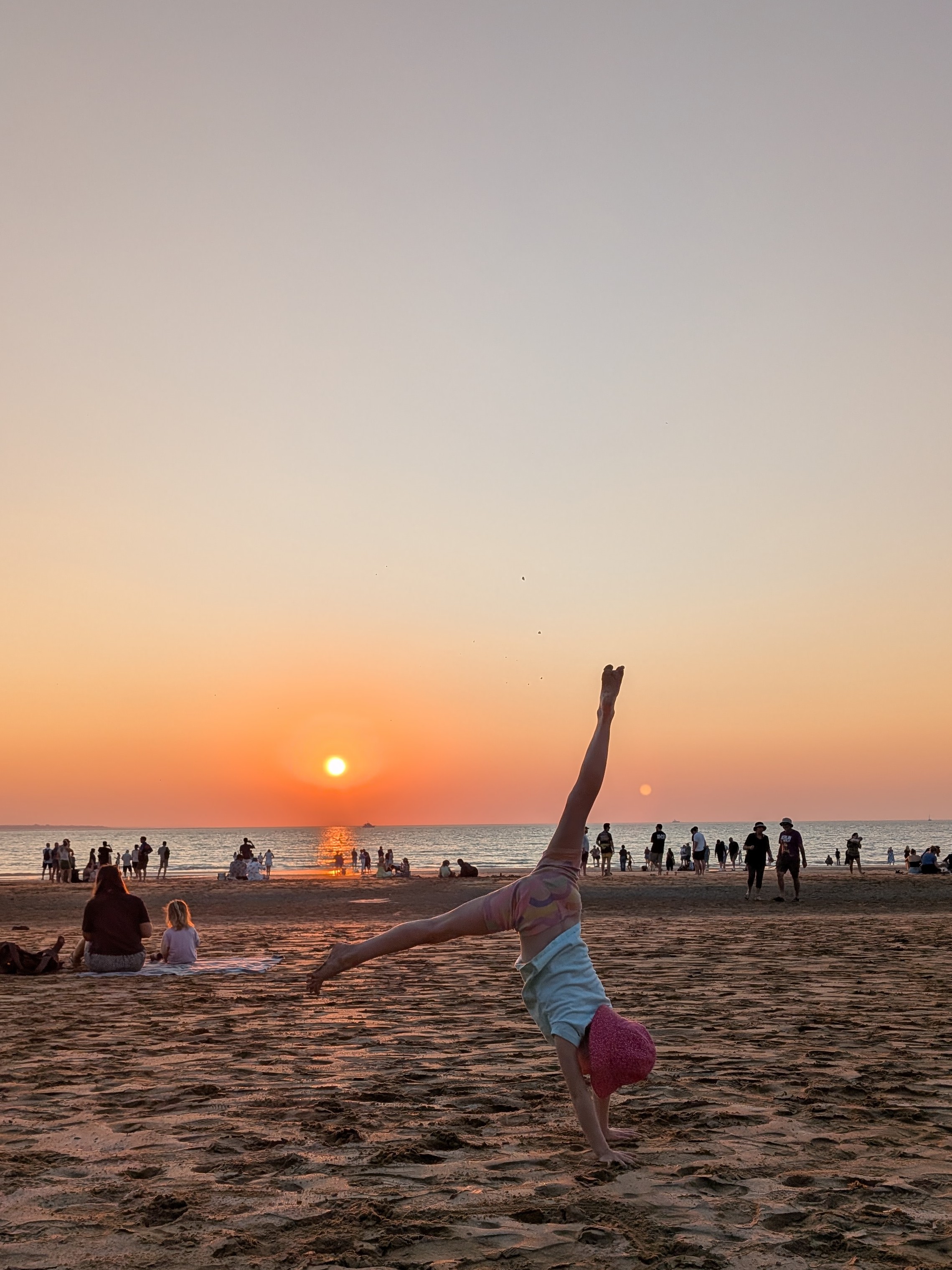 Hazel mid-cartwheel against the sunset, sand flying off her toes