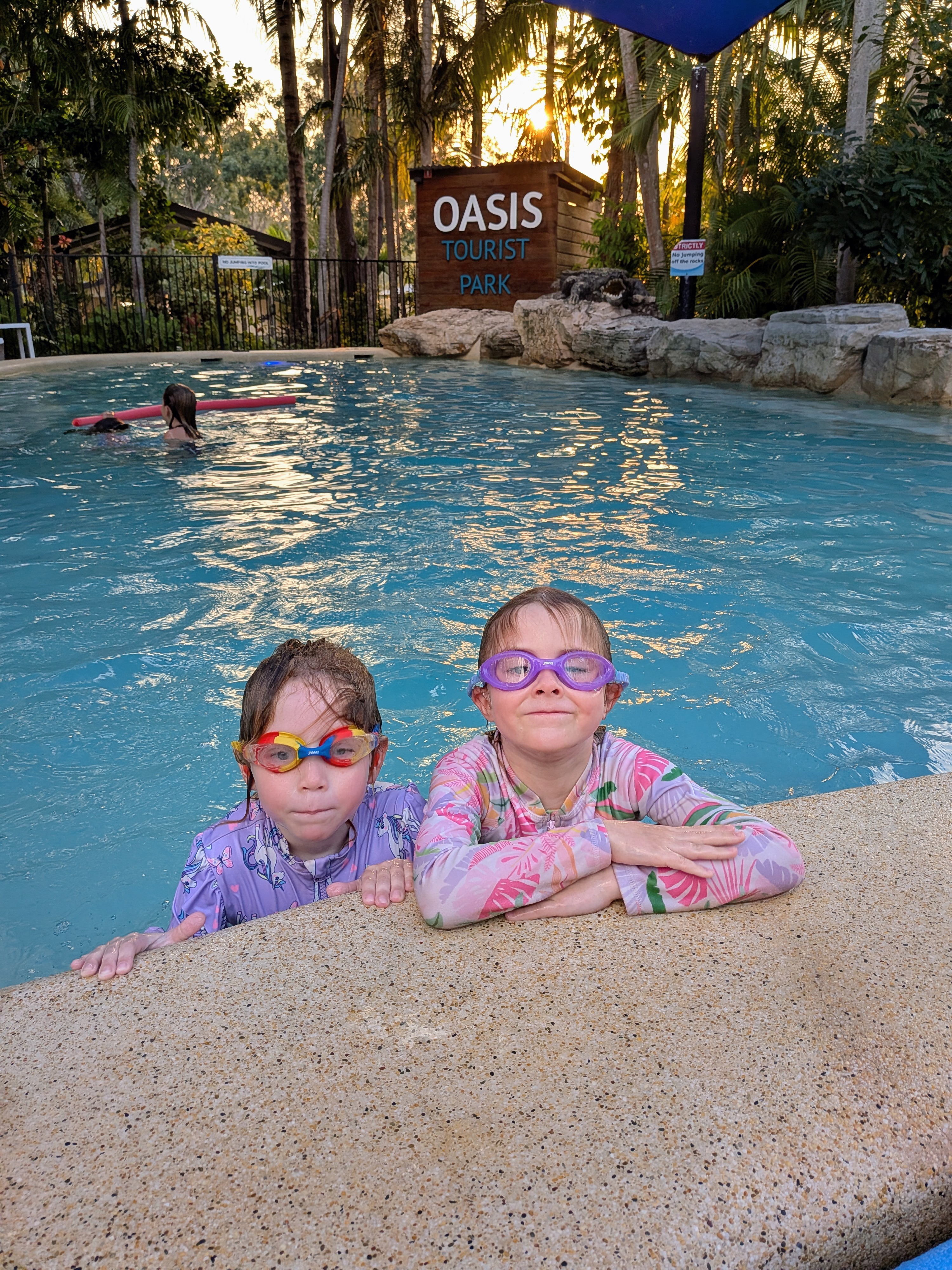 Hazel and Leah in their goggles at the edge of the Oasis Tourist Park pool