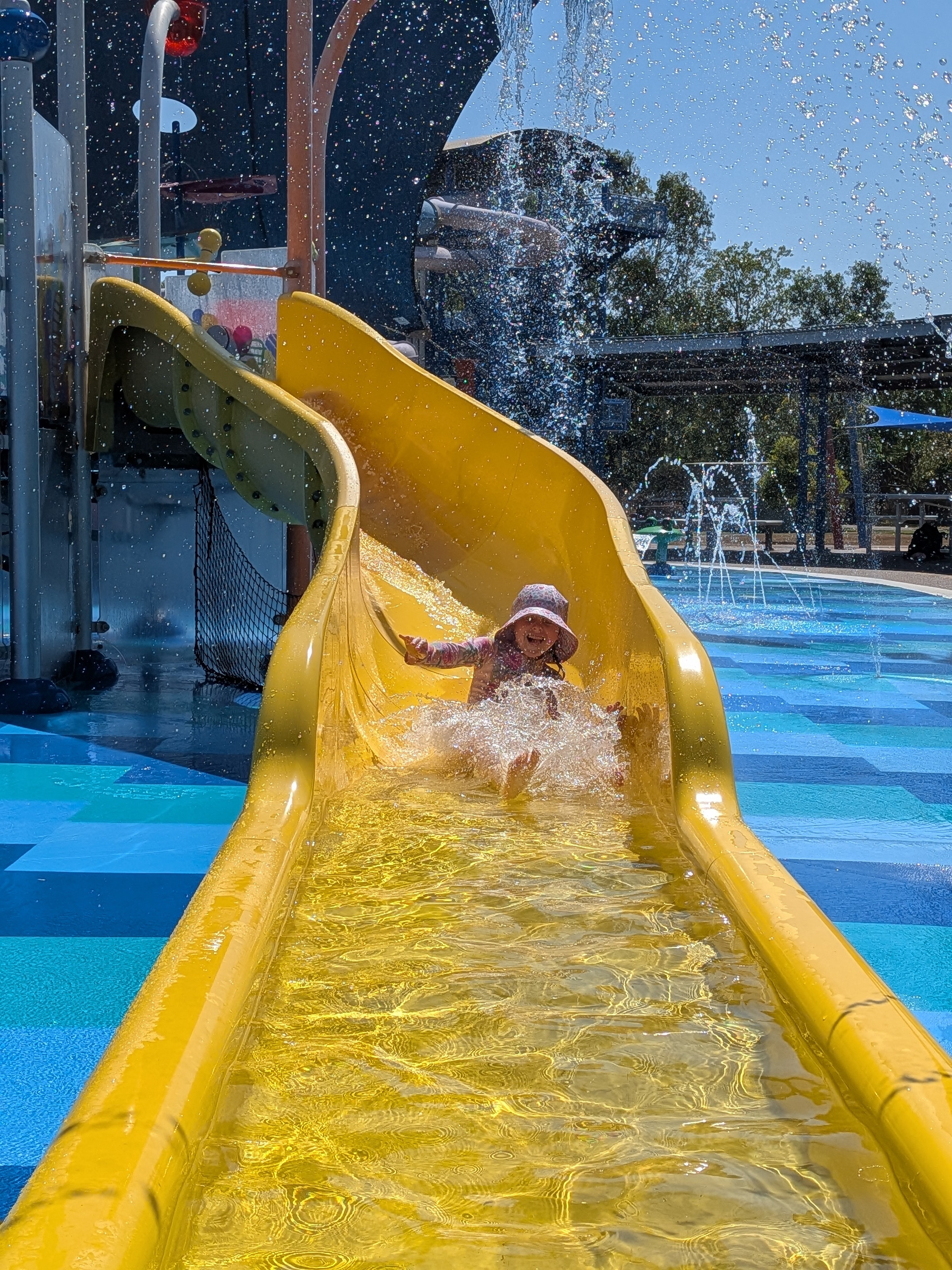 Mid-splash grin on the yellow slide at Leanyer Recreation Park