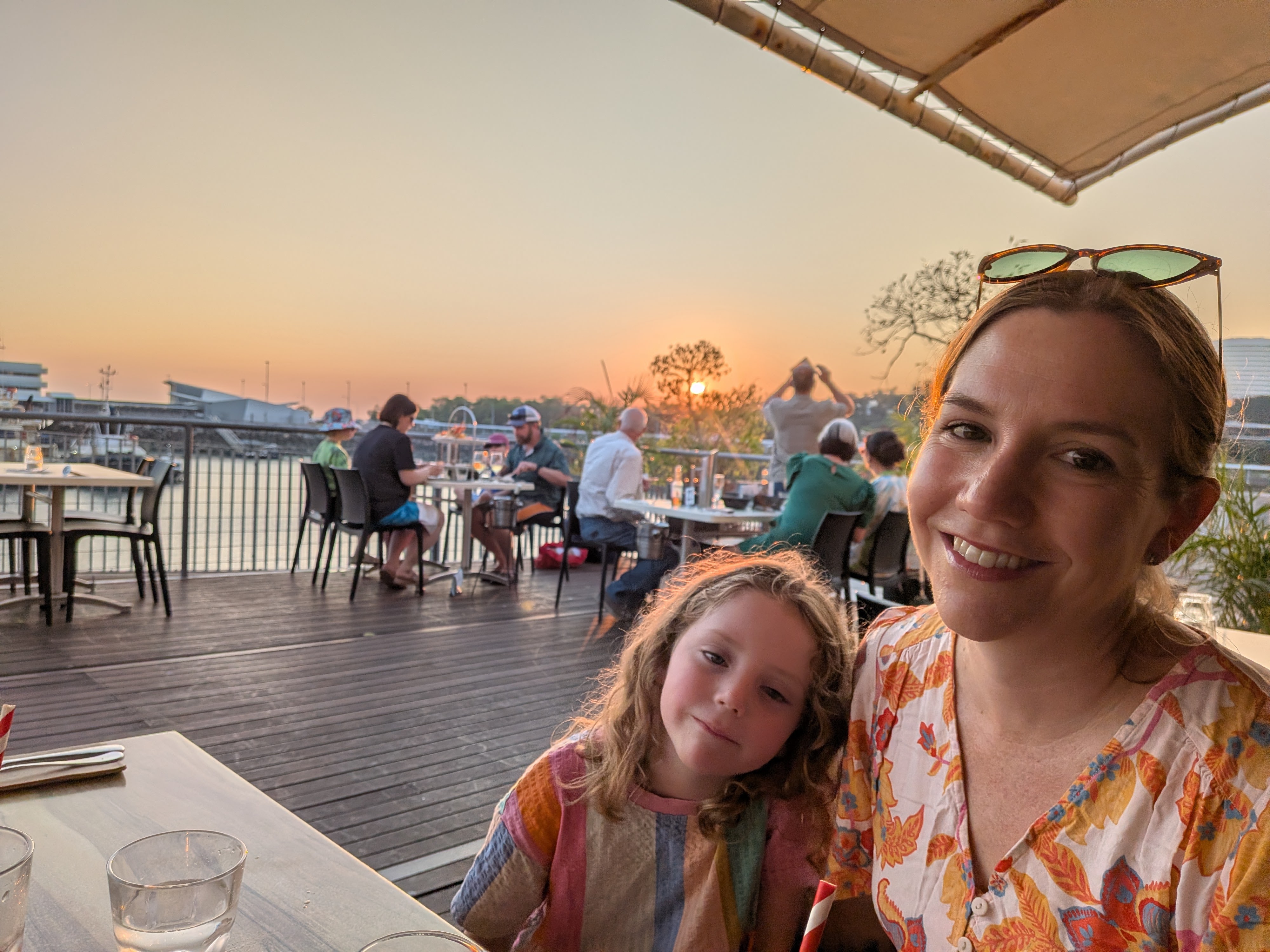Erin and Leah&rsquo;s selfie at the wharf dinner table, sunset glowing behind