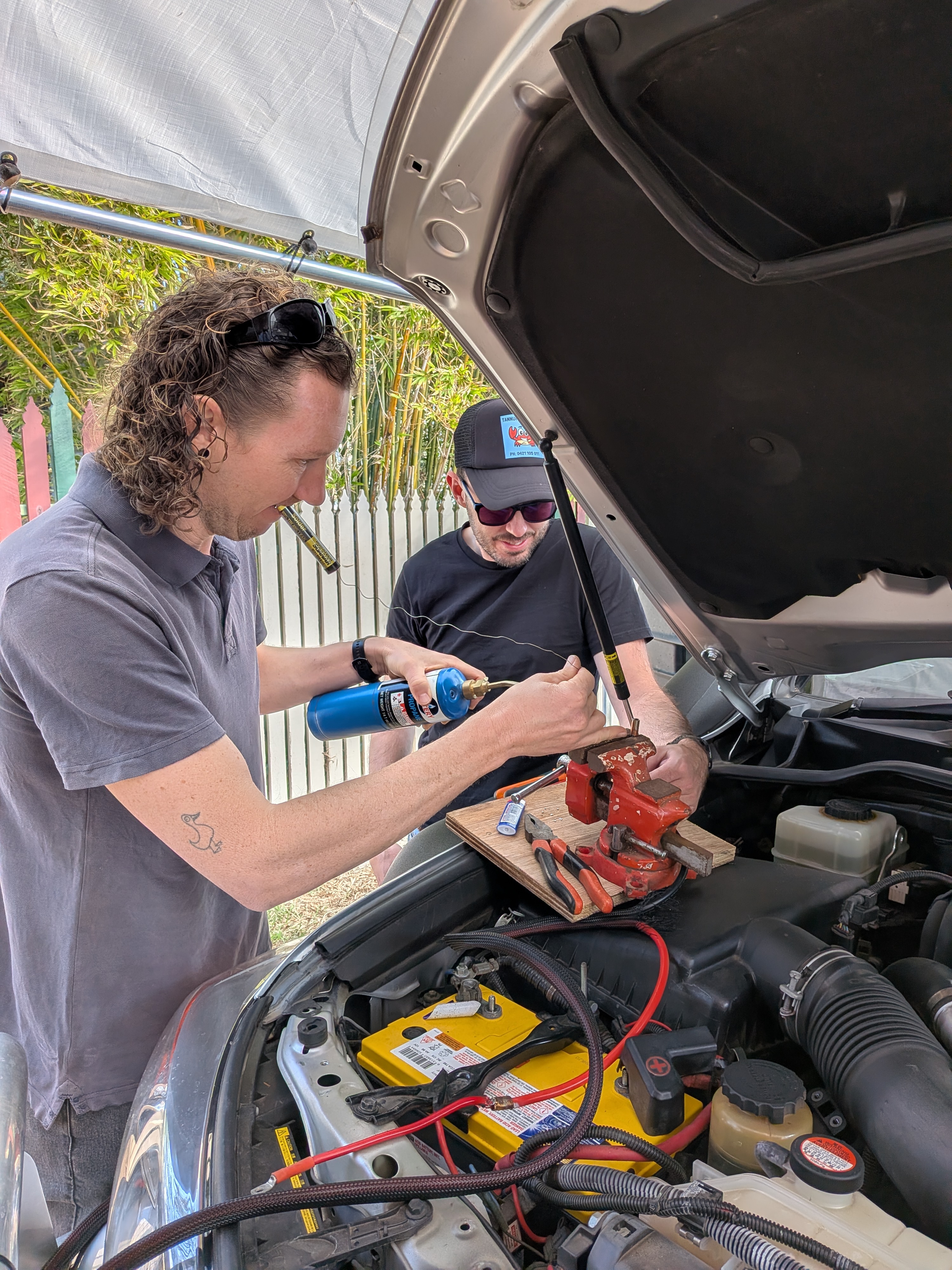 Dylan and James doing dodgy DIY auto-electrics under Reg's bonnet