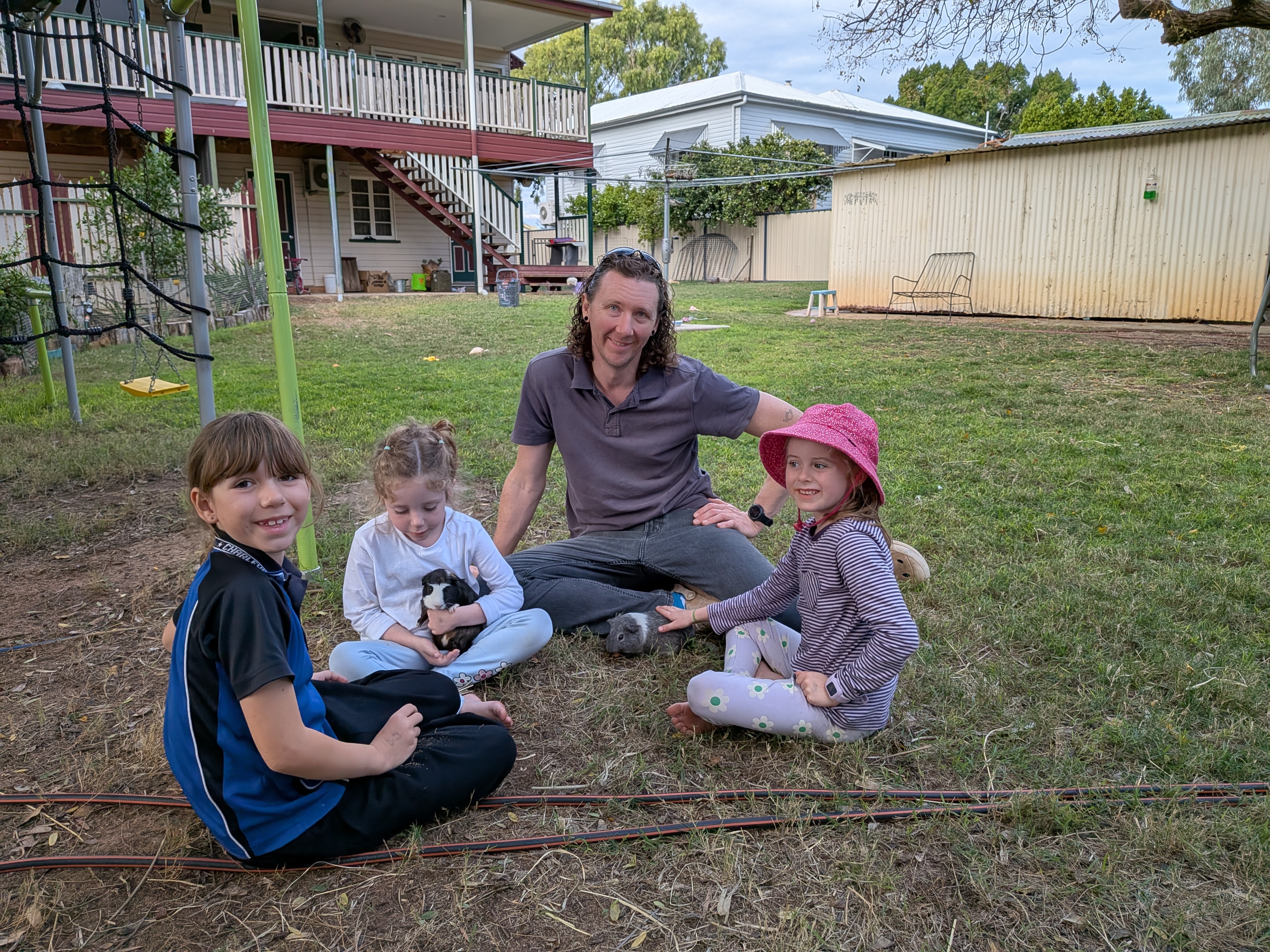 Dylan and the kids sitting in the backyard with guinea pigs