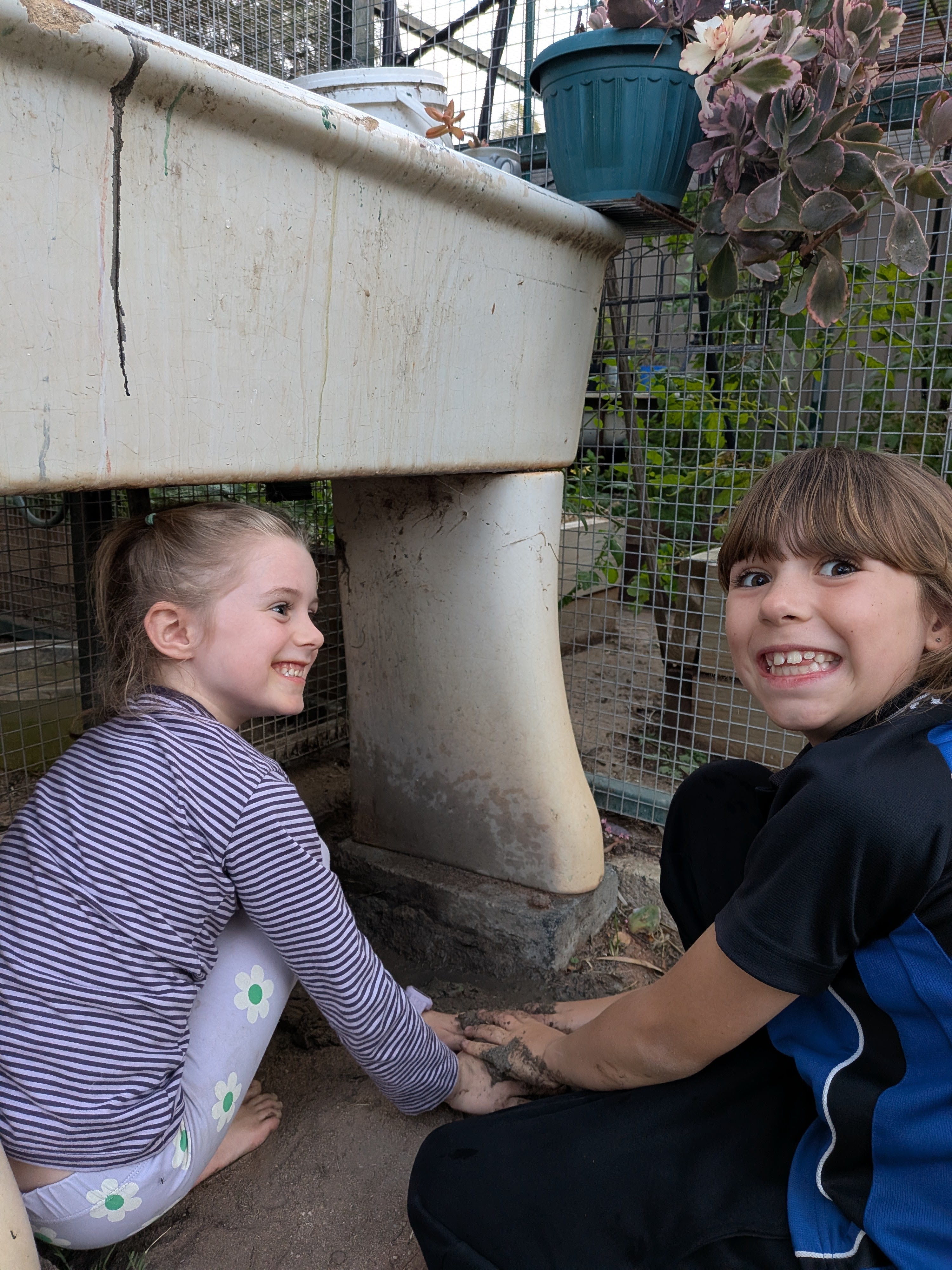 The girls grinning by the chicken coop