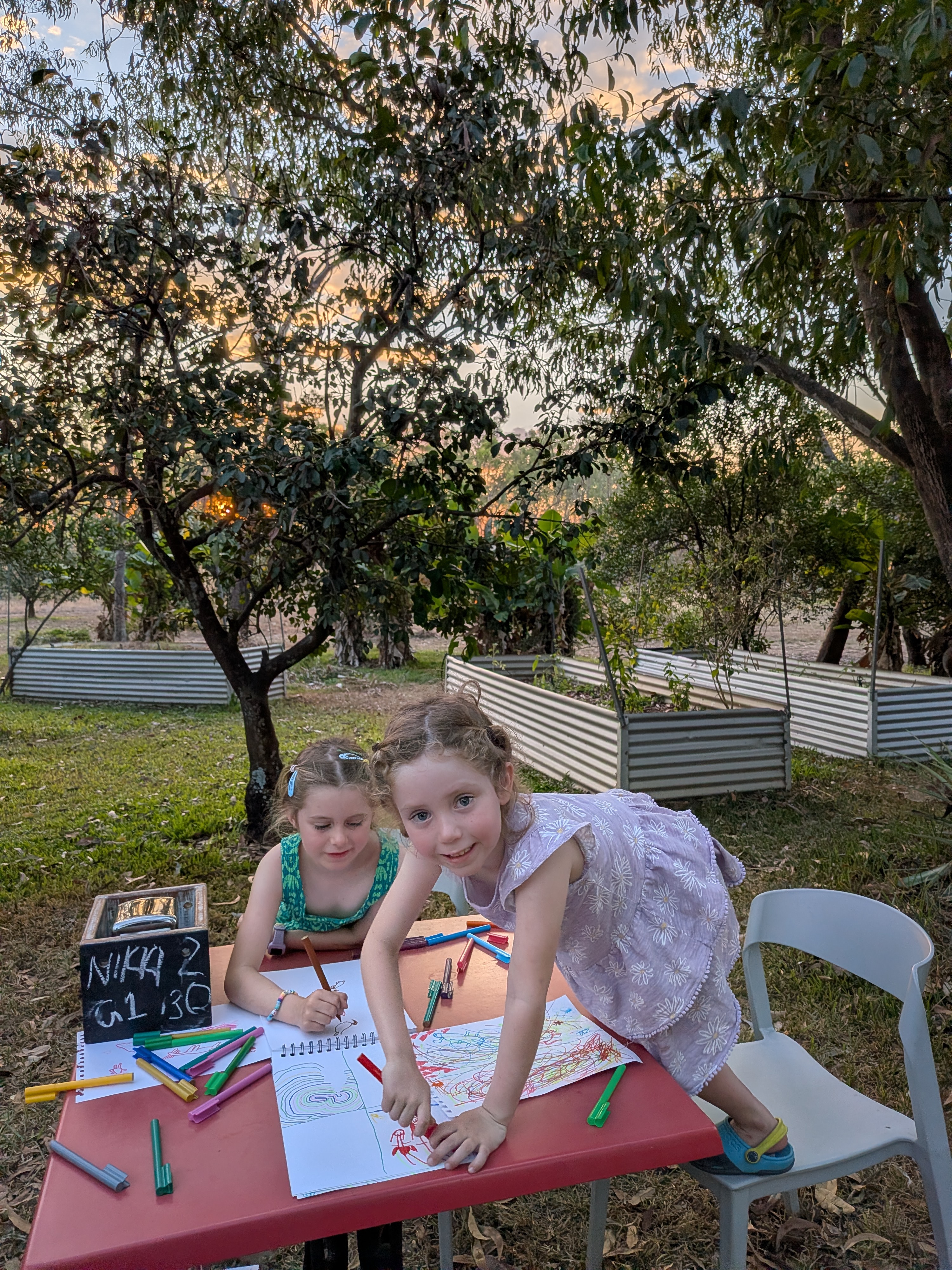 Hazel and Leah drawing at the brewery as the sun sets behind the garden