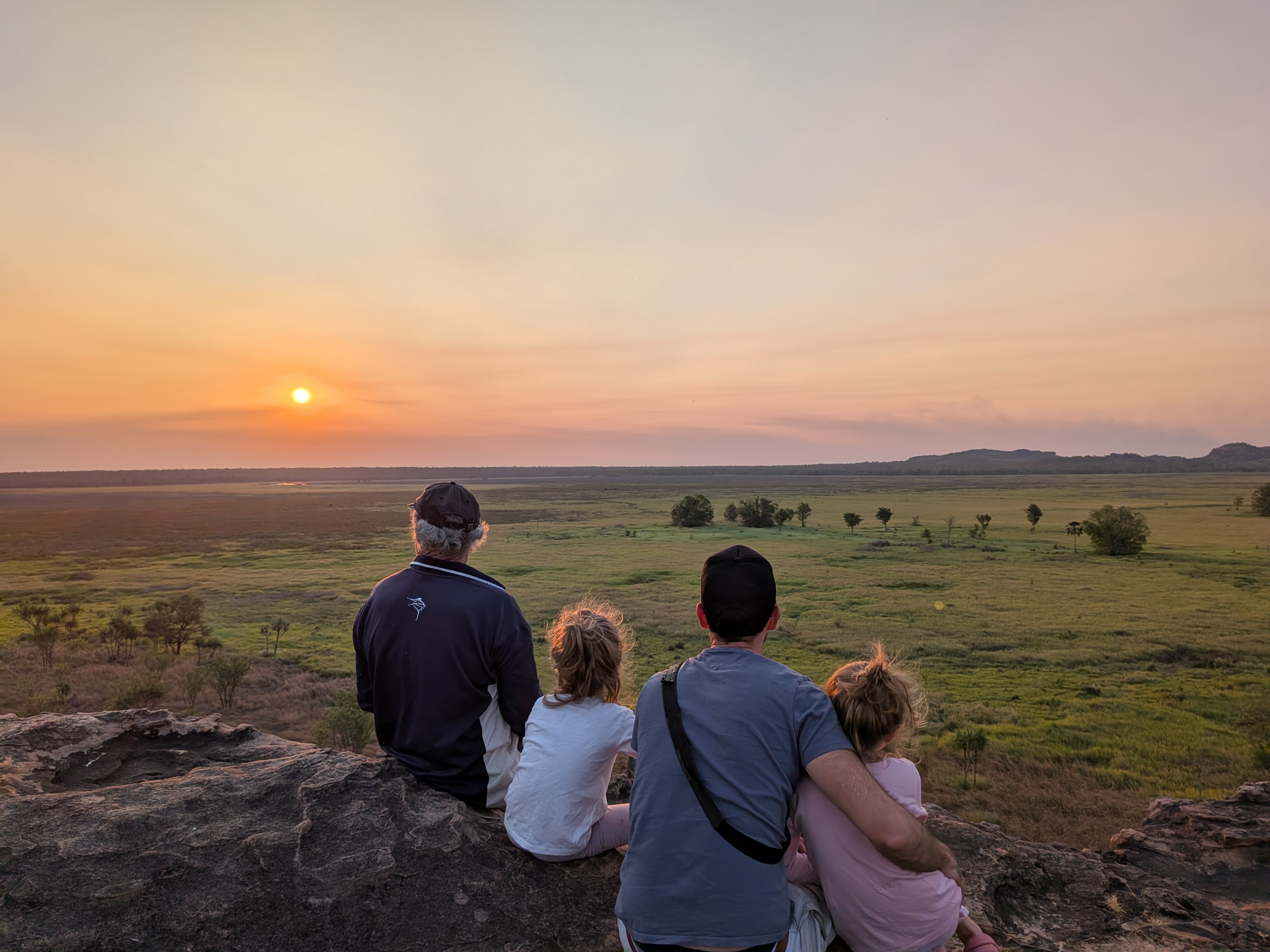 Huddled together on the rock as the sky turns orange over the floodplain