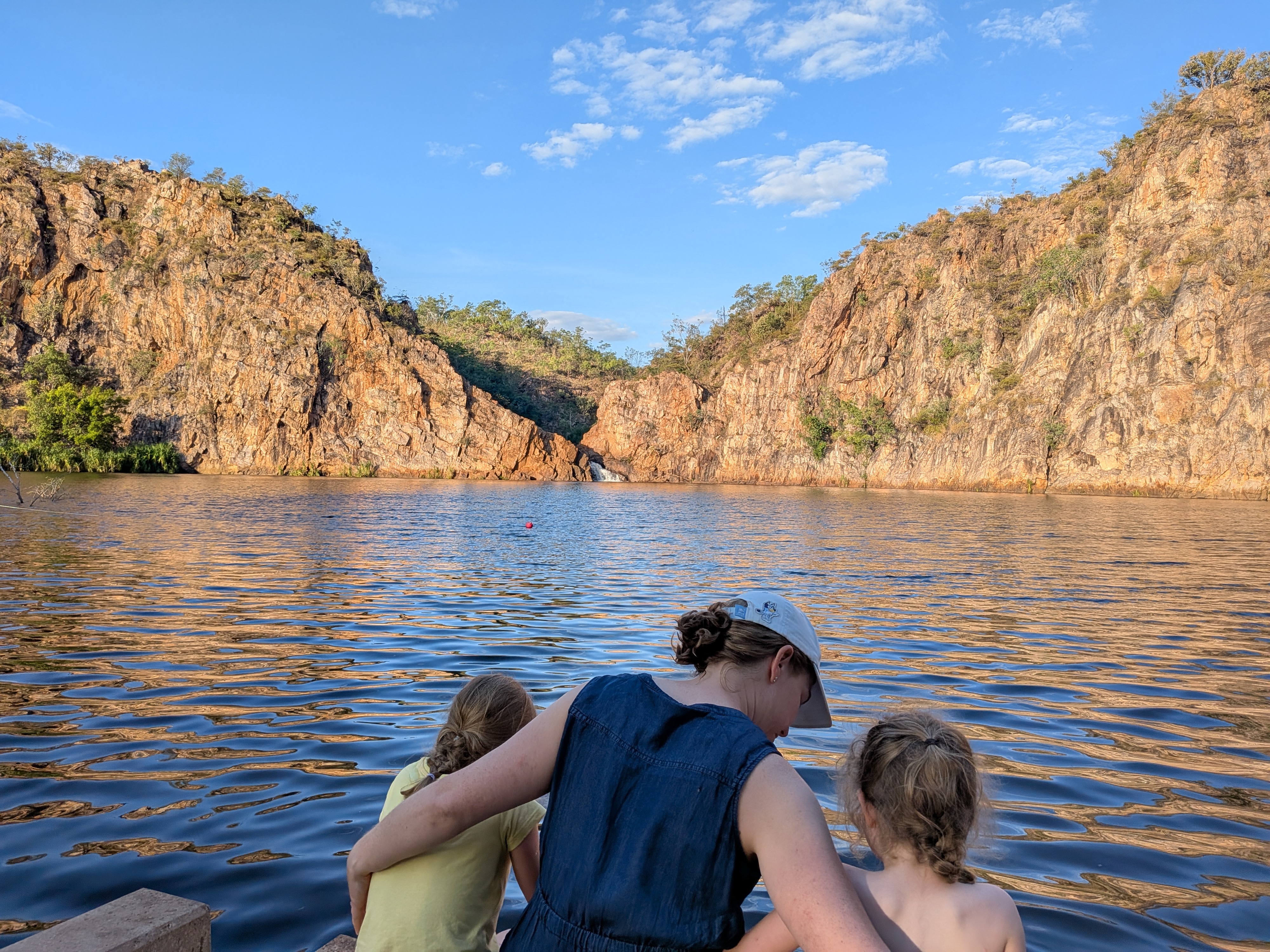 Erin and the girls dipping feet at the water&rsquo;s edge as the cliffs turn gold