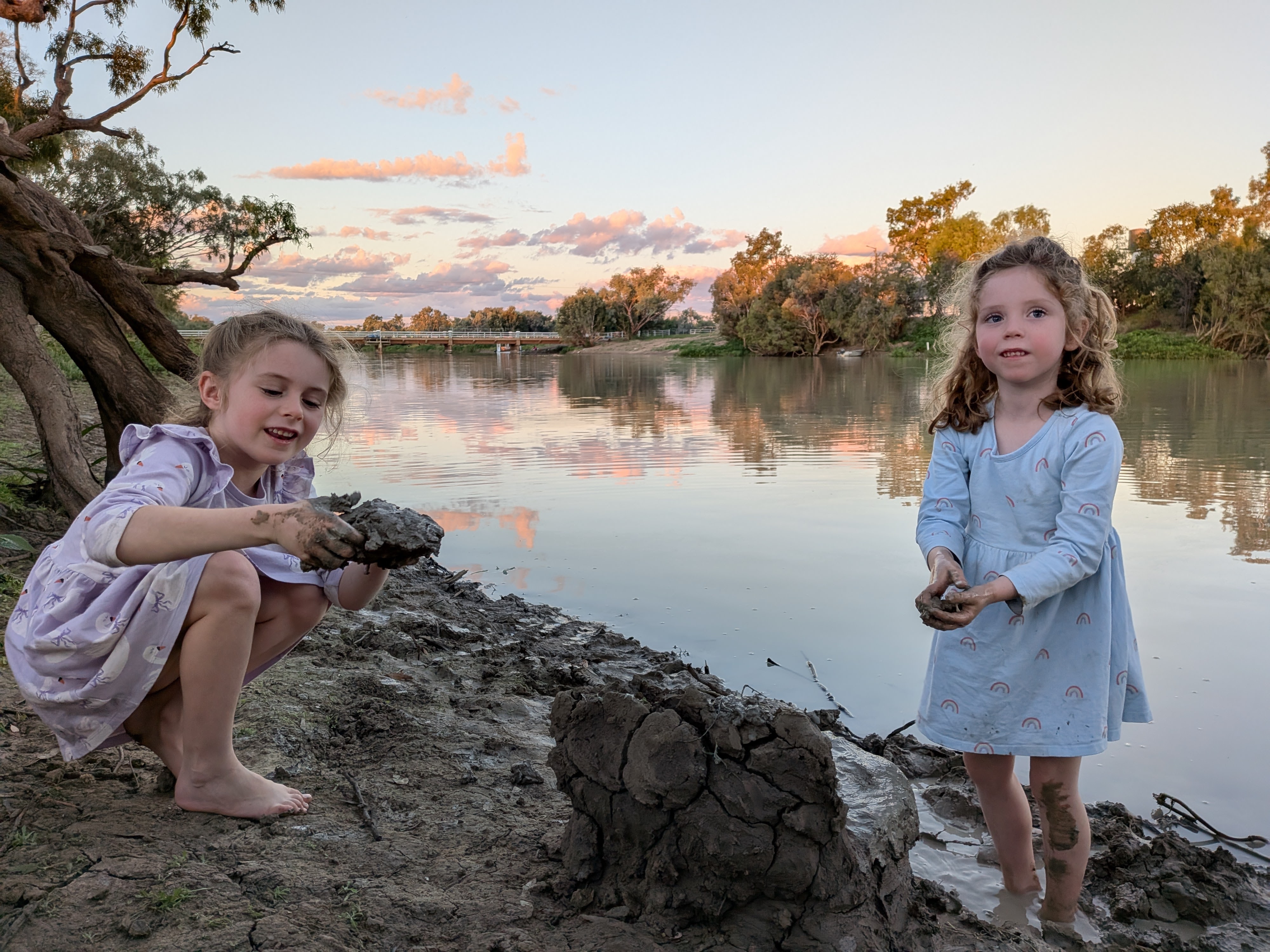 Hazel and Leah playing in the mud by the Thomson River at sunset