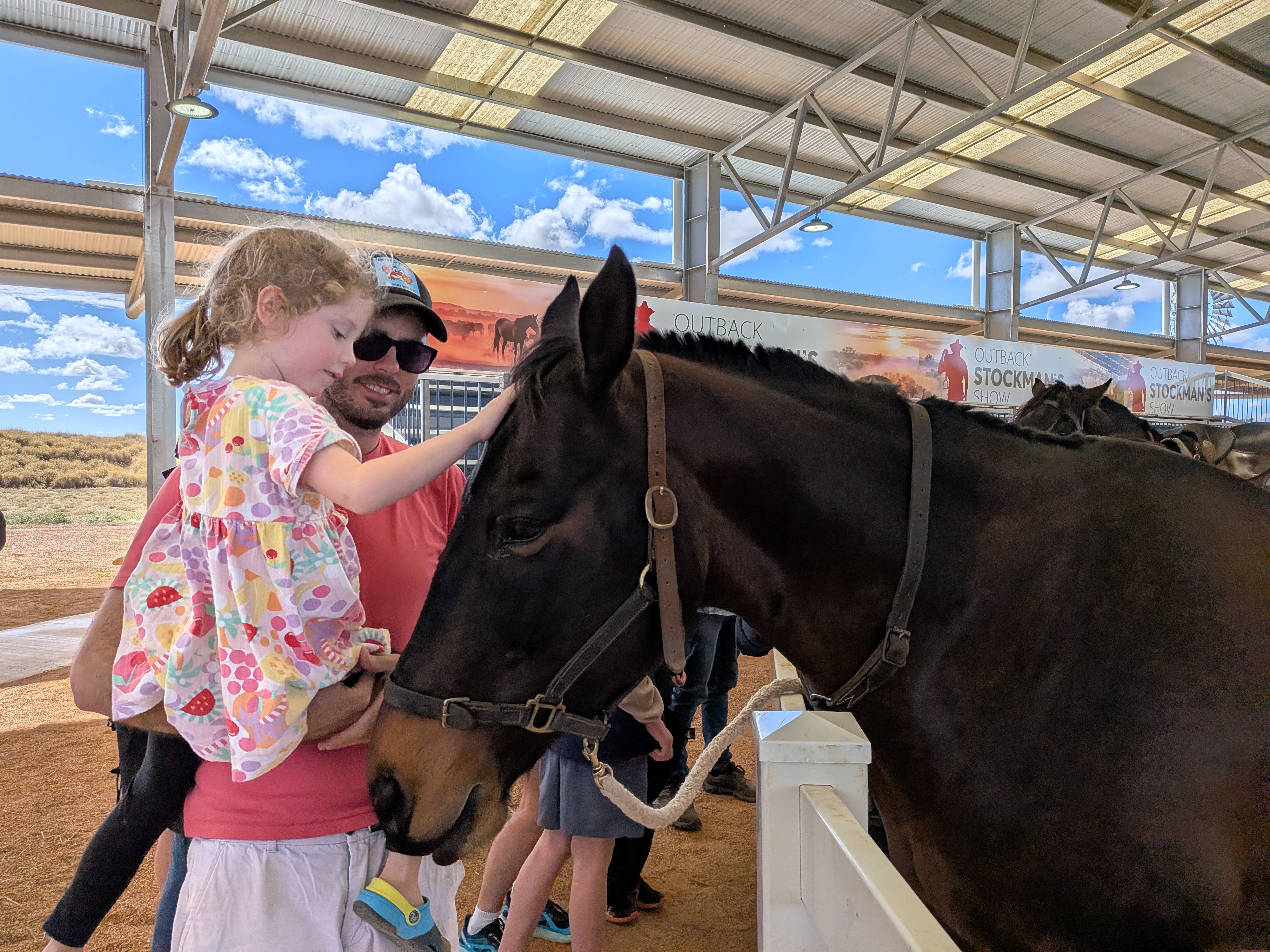 Dylan holding Leah patting a horse at the Stockman's Hall of Fame