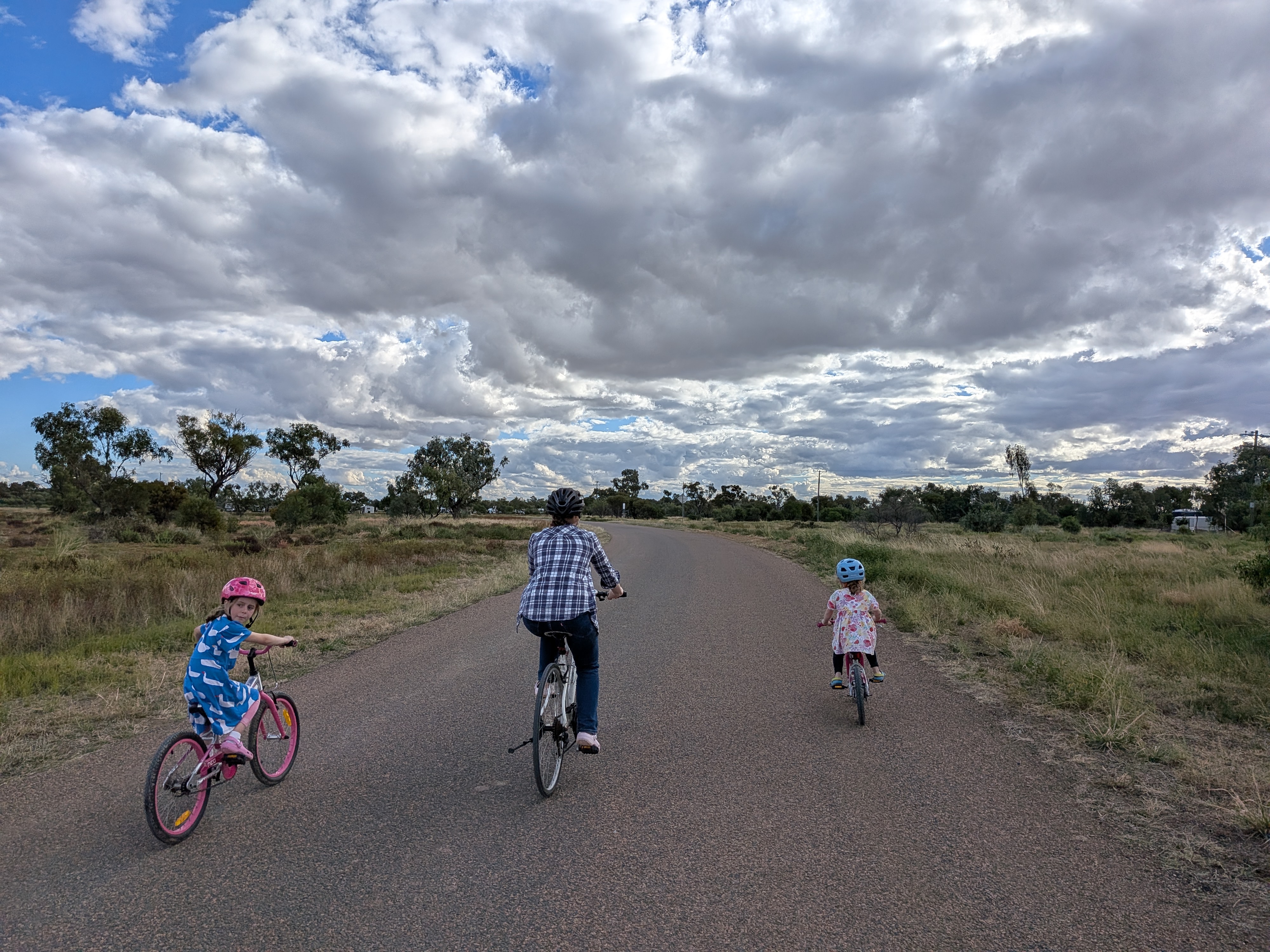 Family bike ride on the road under big outback skies