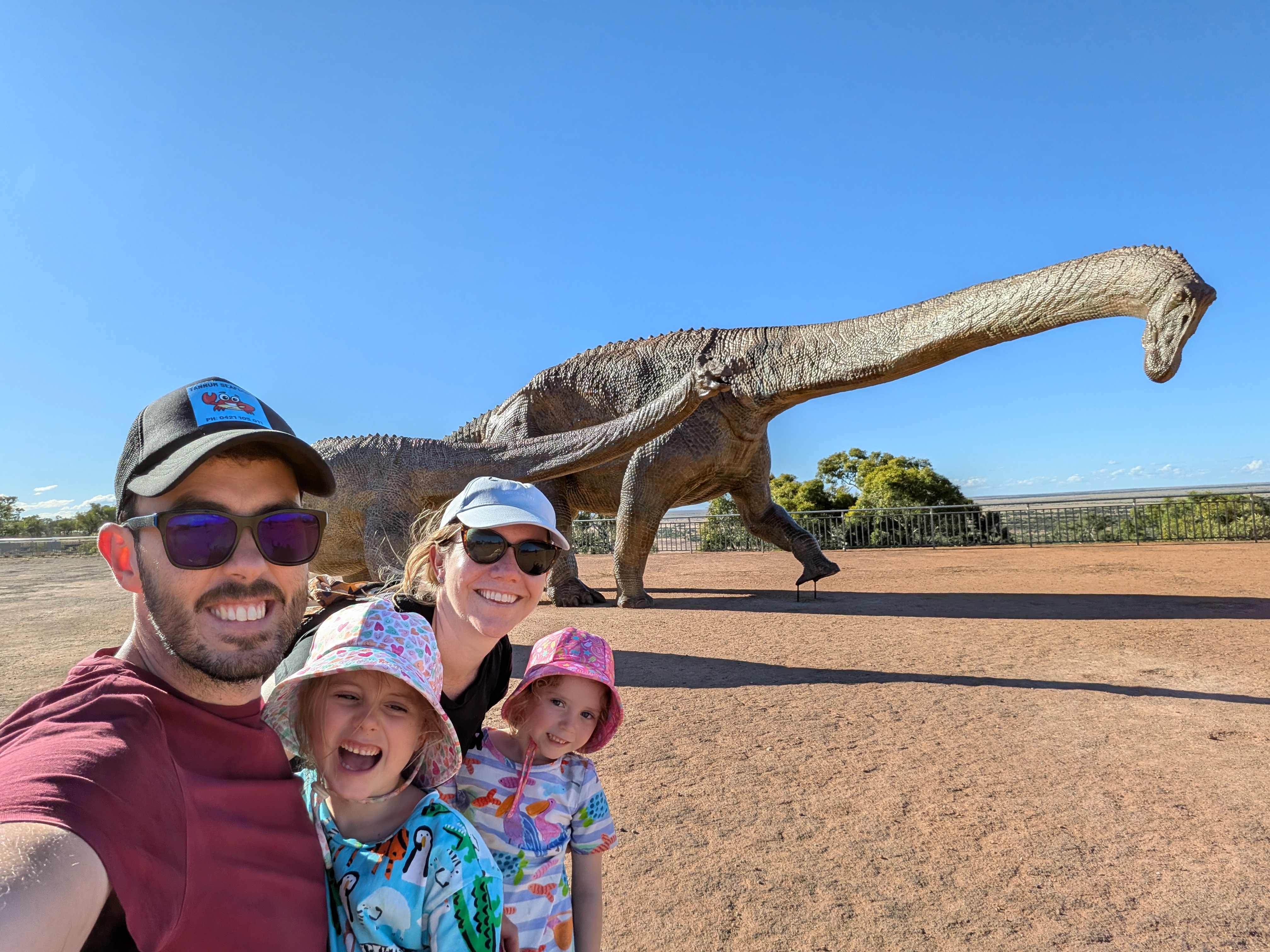 Family selfie with dinosaur sculptures in the background
