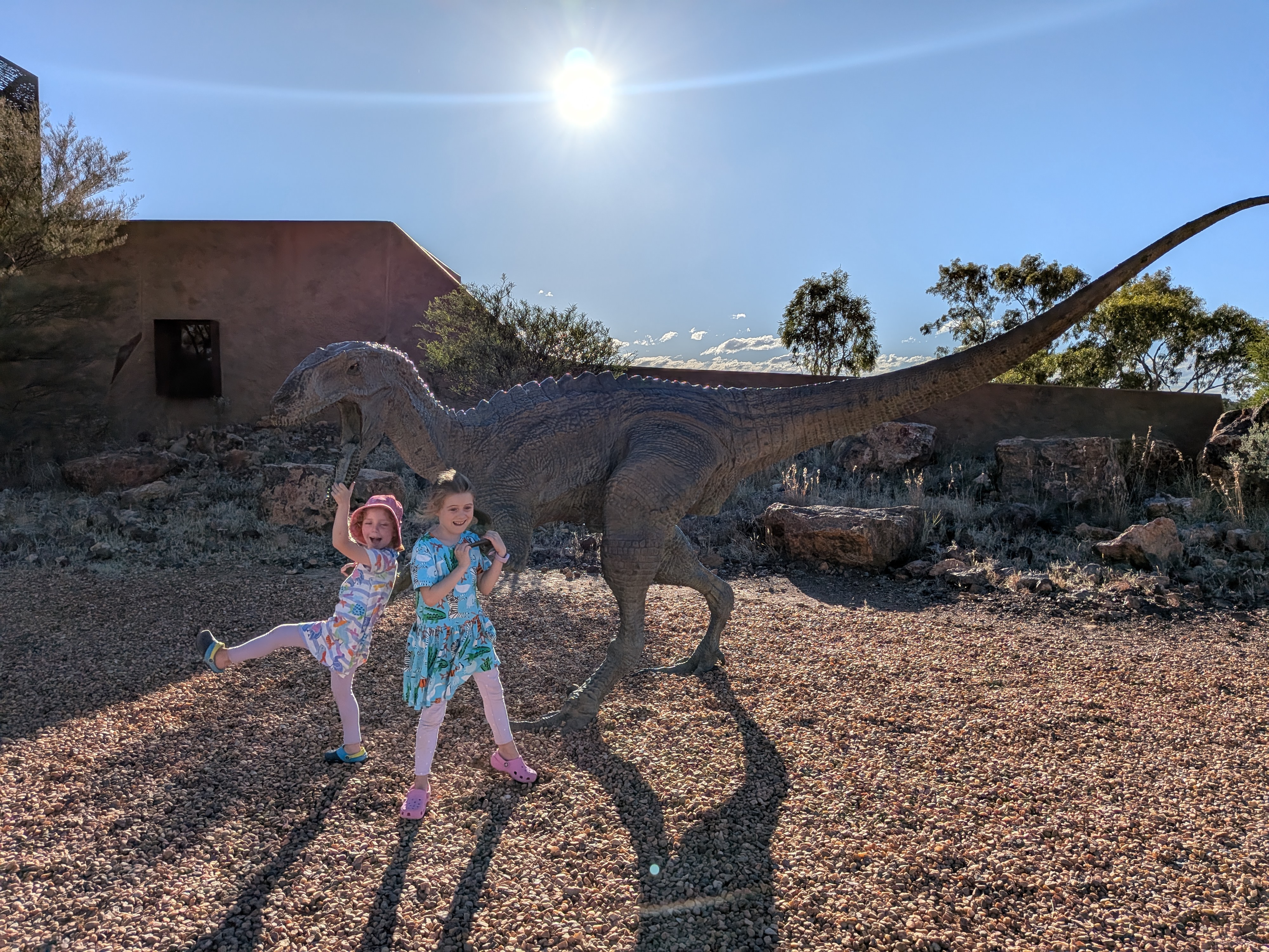 The girls striking poses with a raptor dinosaur sculpture