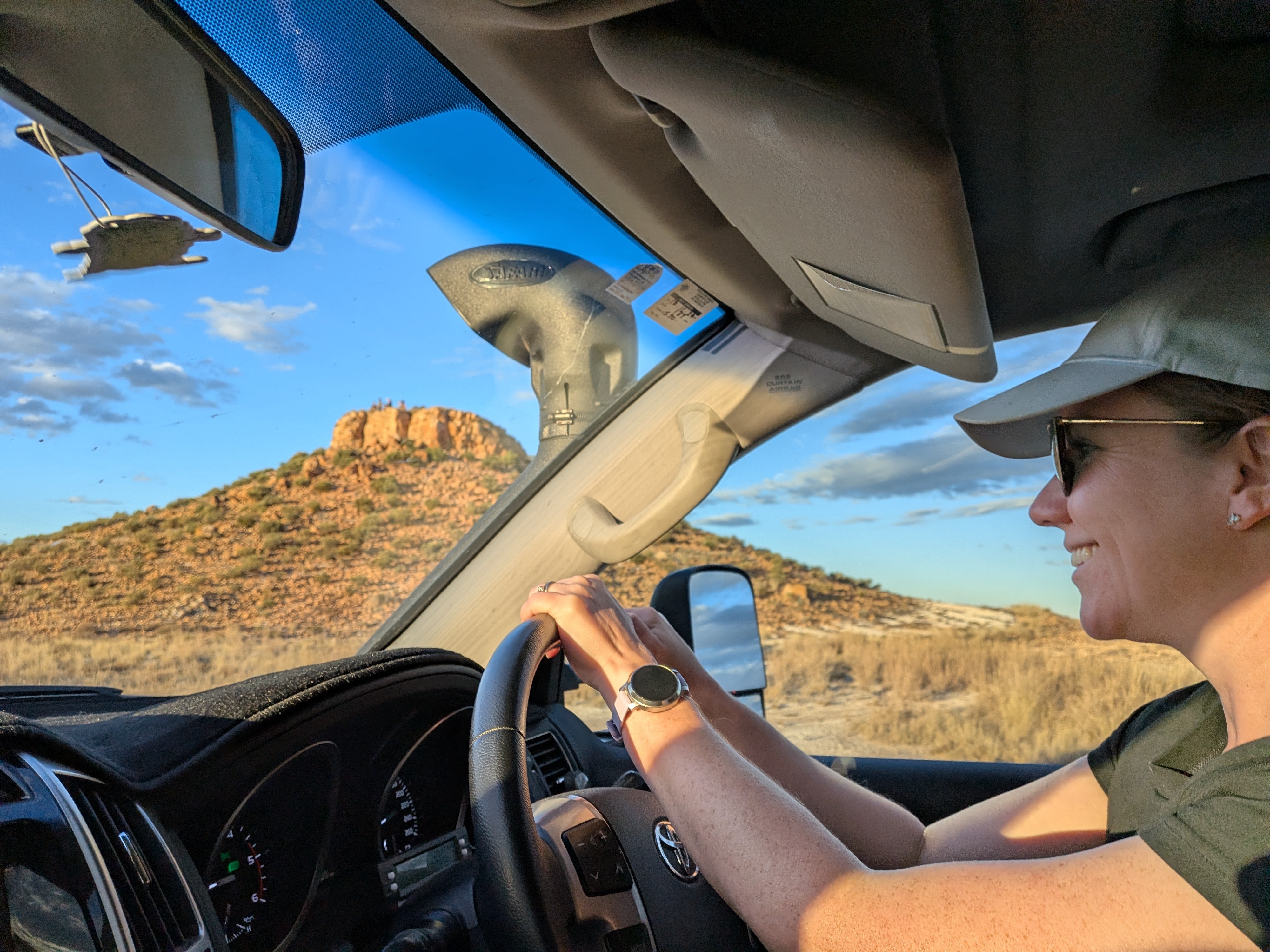 Erin driving Reg with rocky outback mesa in the windscreen
