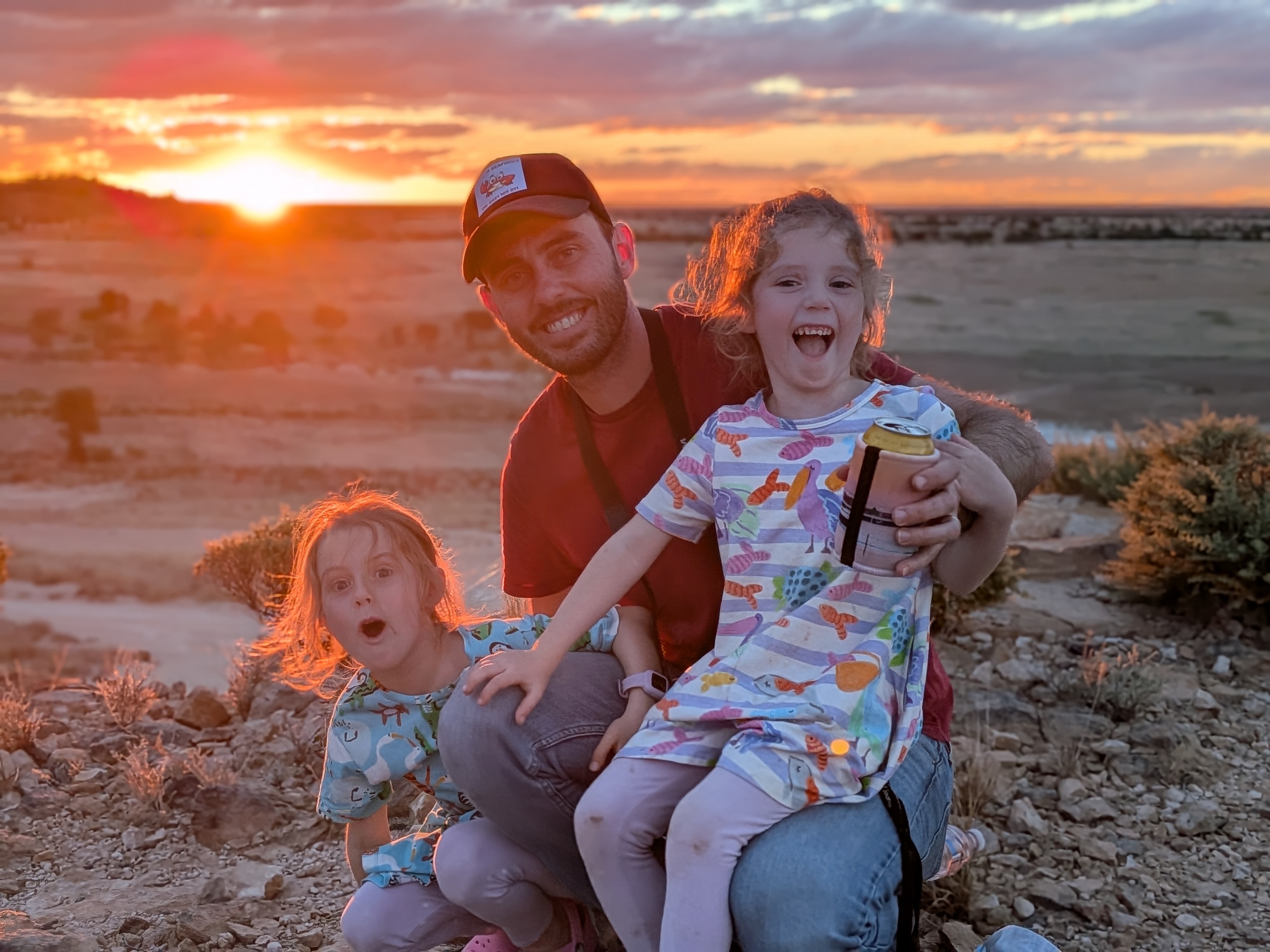 Dylan with the girls at sunset — big smiles at Dinosaur Creek