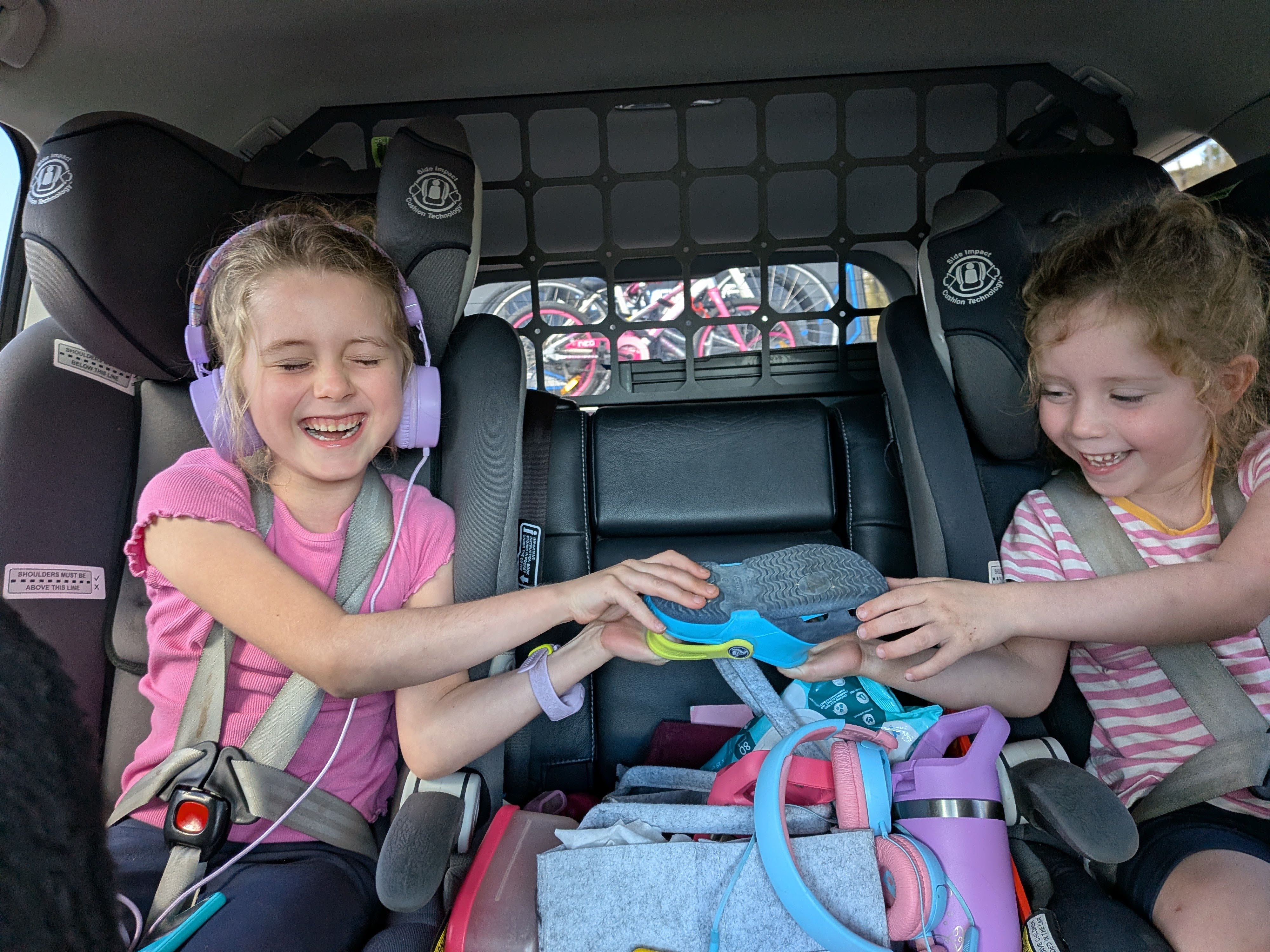 Hazel and Leah laughing in the back seat with headphones