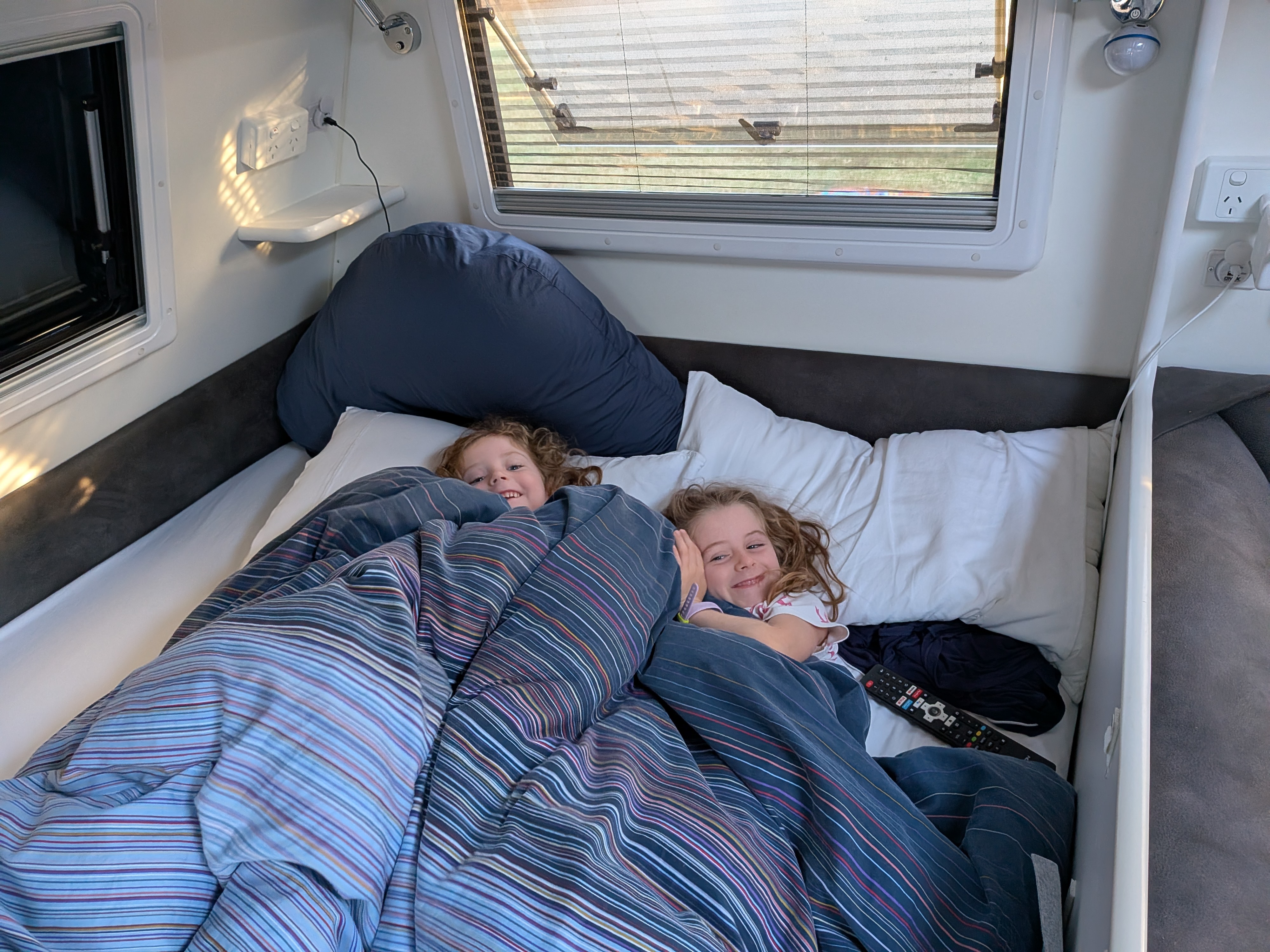 Hazel and Leah cosy in bed in the caravan