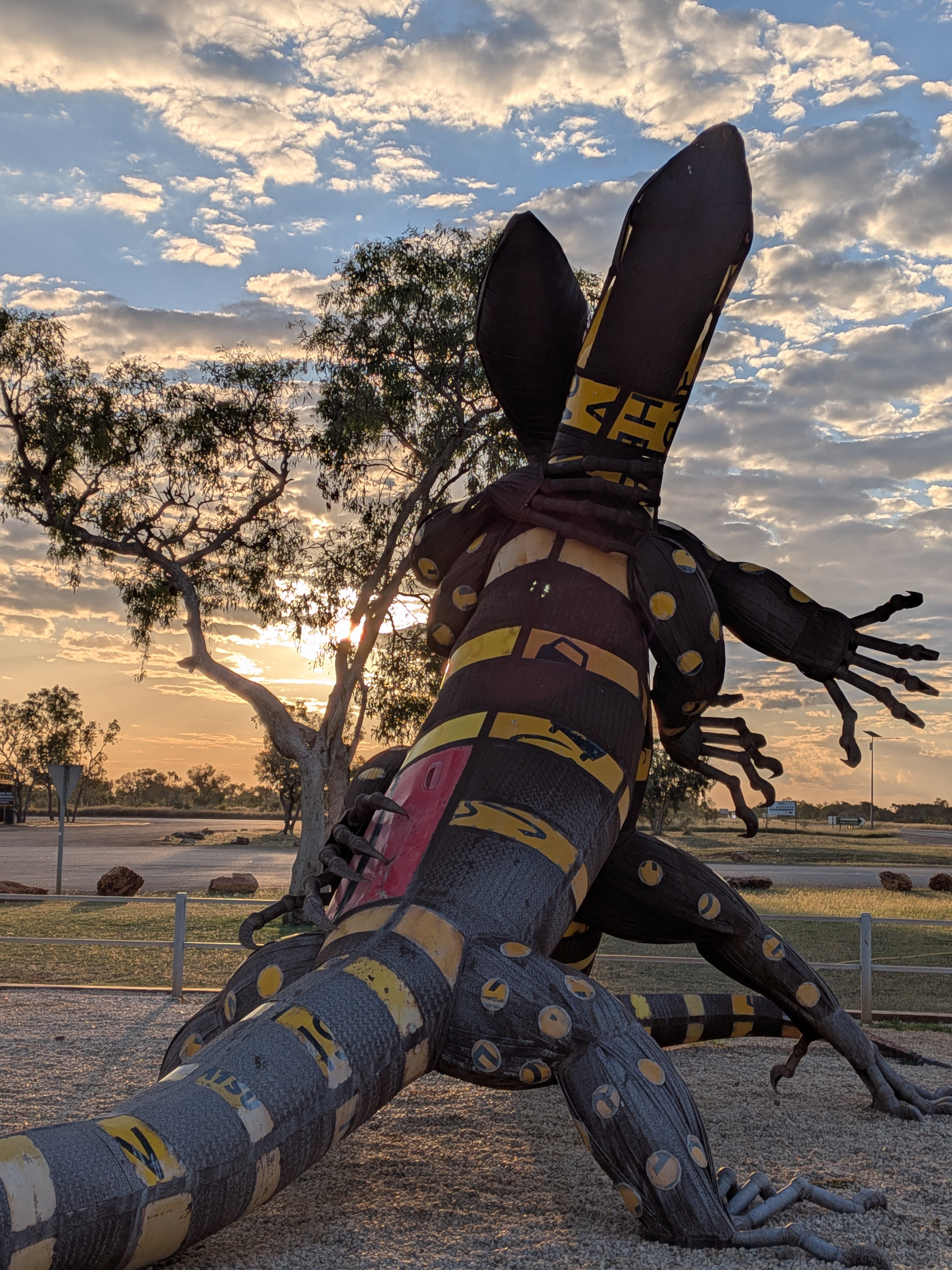 Giant goanna sculpture silhouetted against the sunset sky