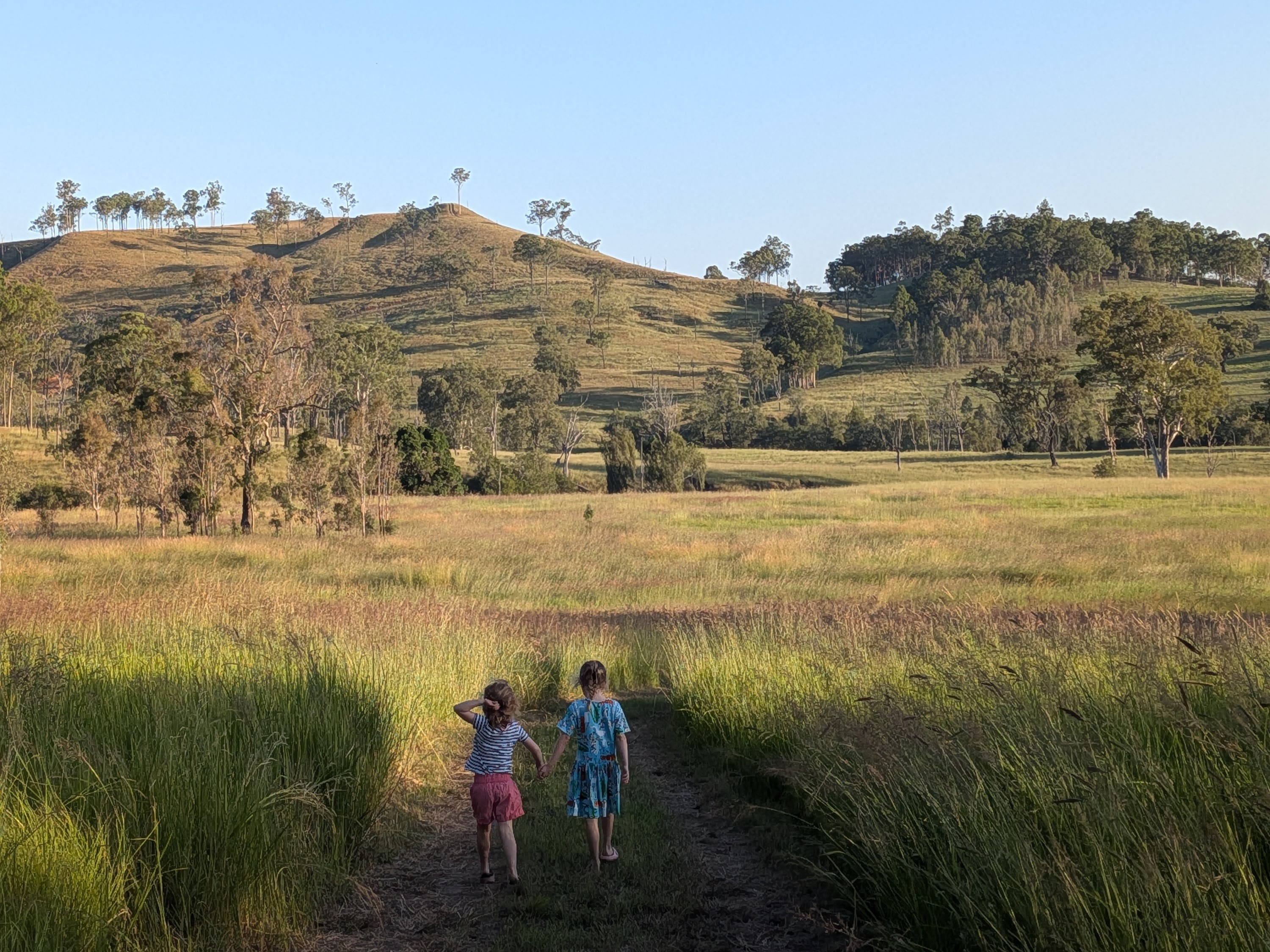 The girls walking hand-in-hand down a track at golden hour